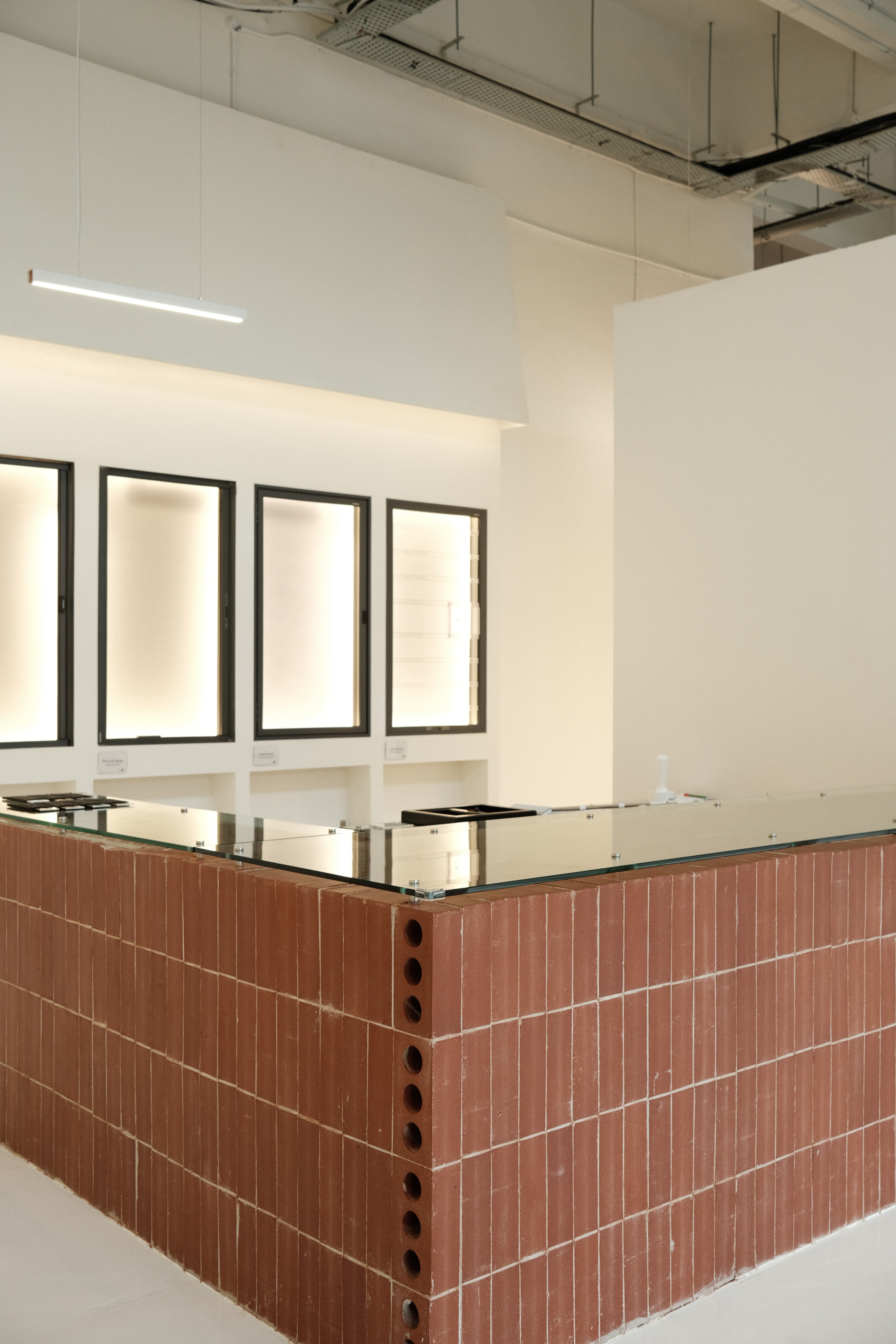 A minimalist counter crafted from warm terracotta brick and topped with glass, balancing tactile materiality with clean, modern lines.