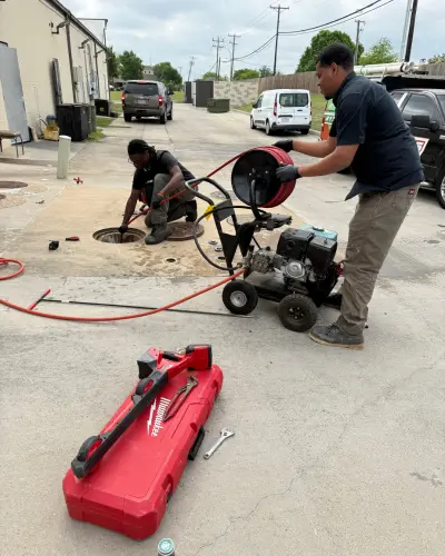 two plumbers cleaning drain on a commercial property