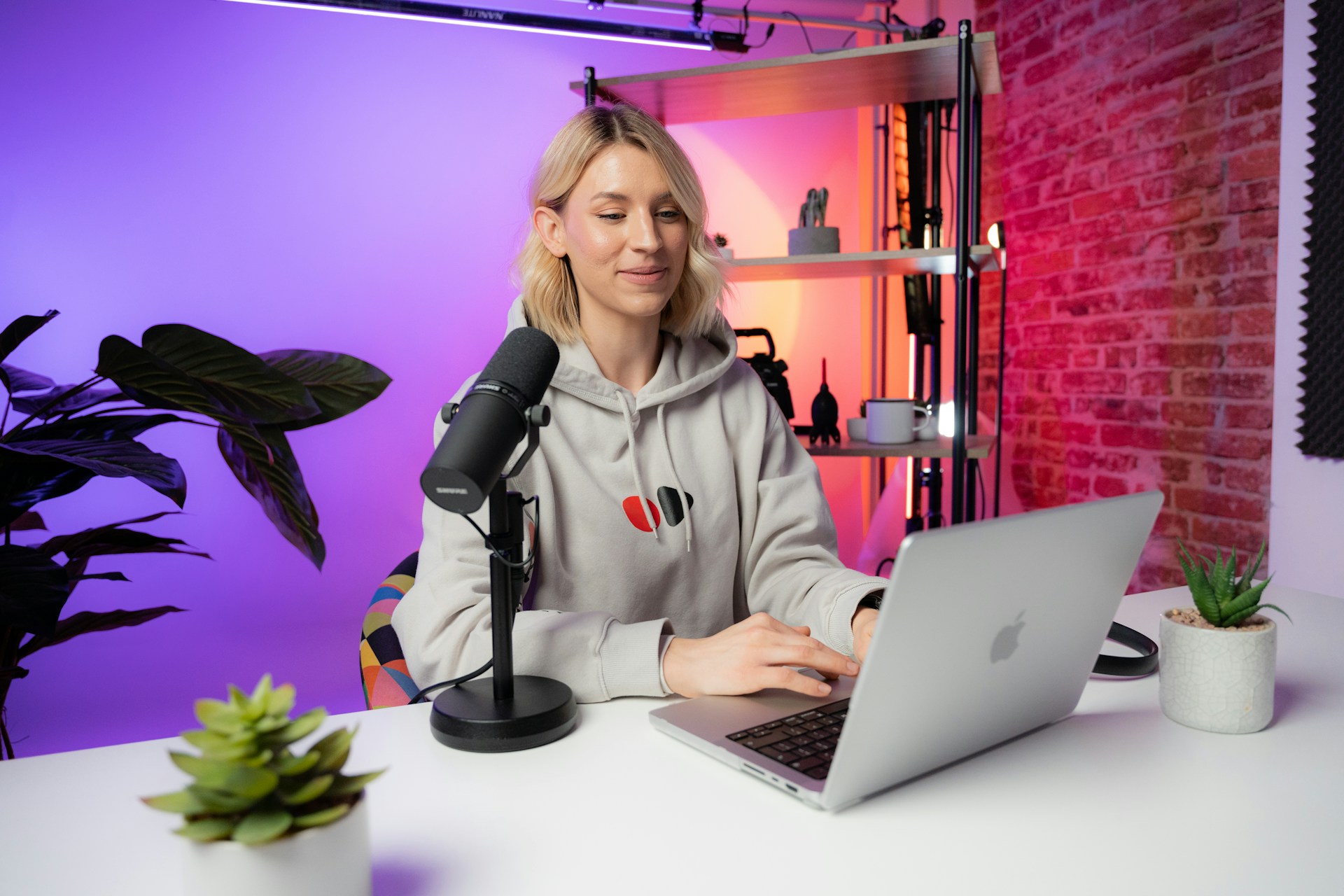 a woman sitting behind a laptop with a mic on the table