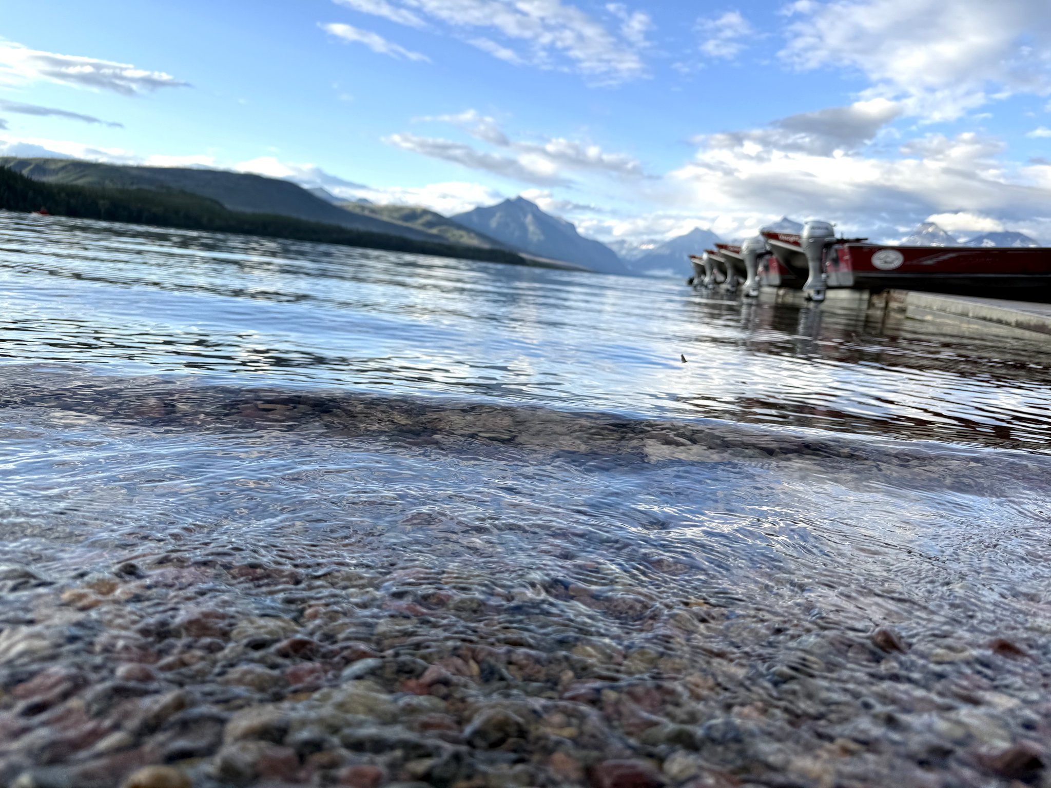 Boats docked on Lake McDonald in Glacier National Park at evening, with mountains rising behind the water
