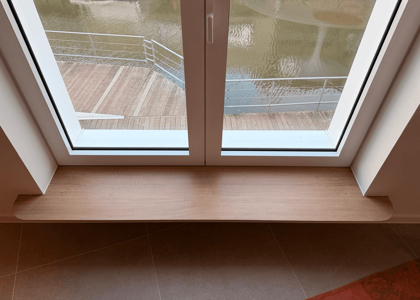 Een grote vensterbank uit eikenhout waardoor het raam geschikt wordt om comfortabel voor te zitten en van het uitzicht te genieten
