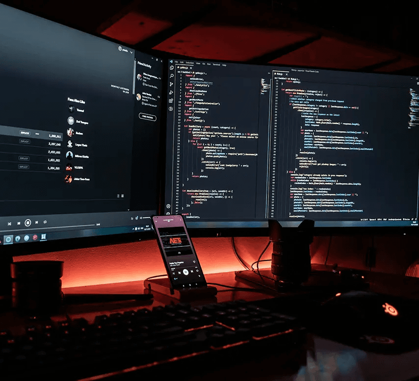 Desktop computer displaying lines of code on screen with a vibrant red LED-lit background