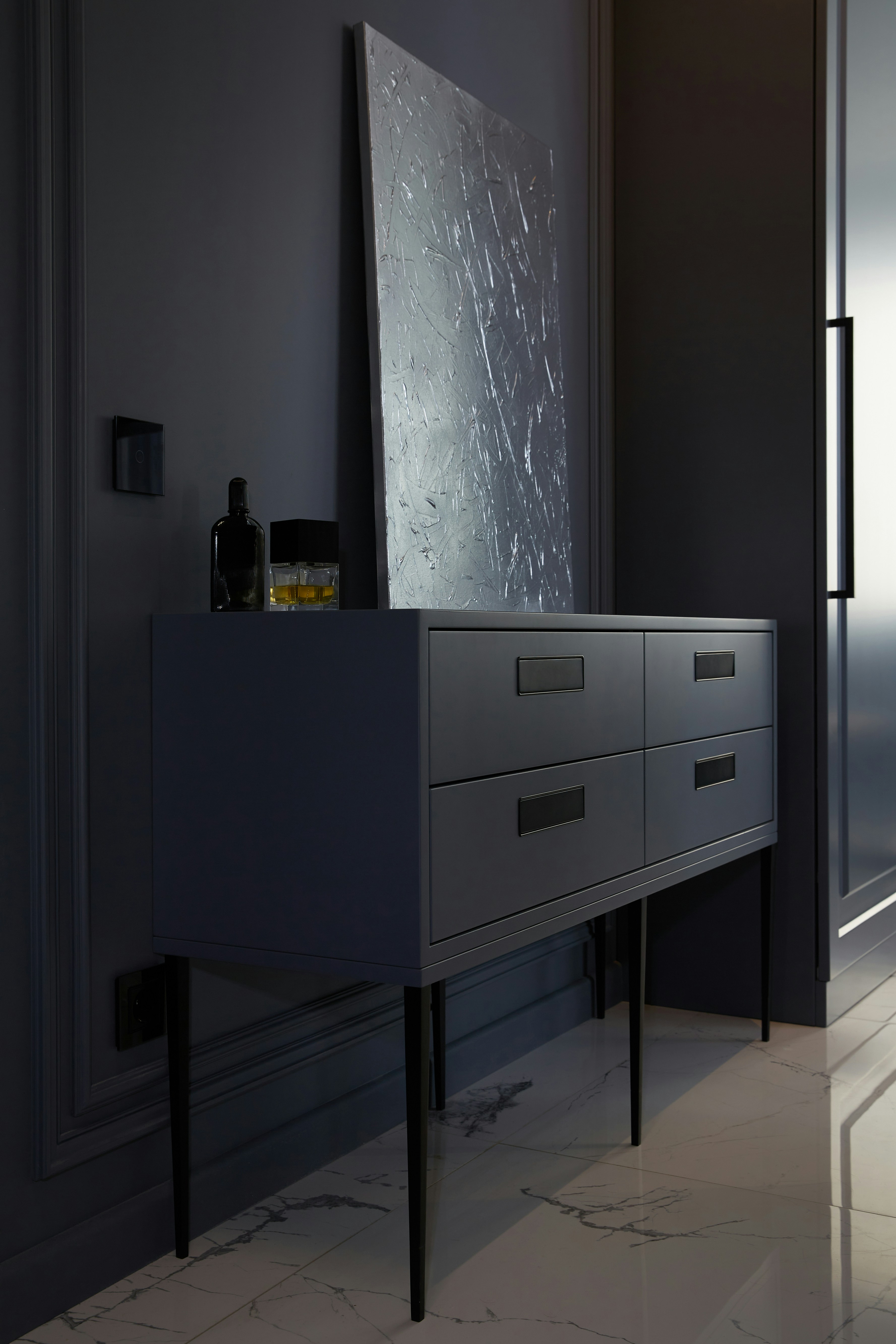 A dark dresser with artwork and bottles.