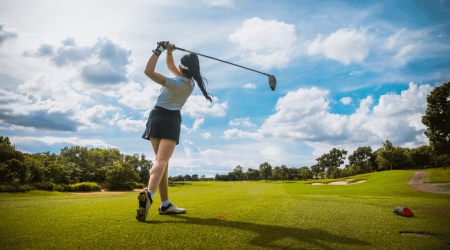 Female golfer practicing her swing follow-through during a professional golf coaching course.