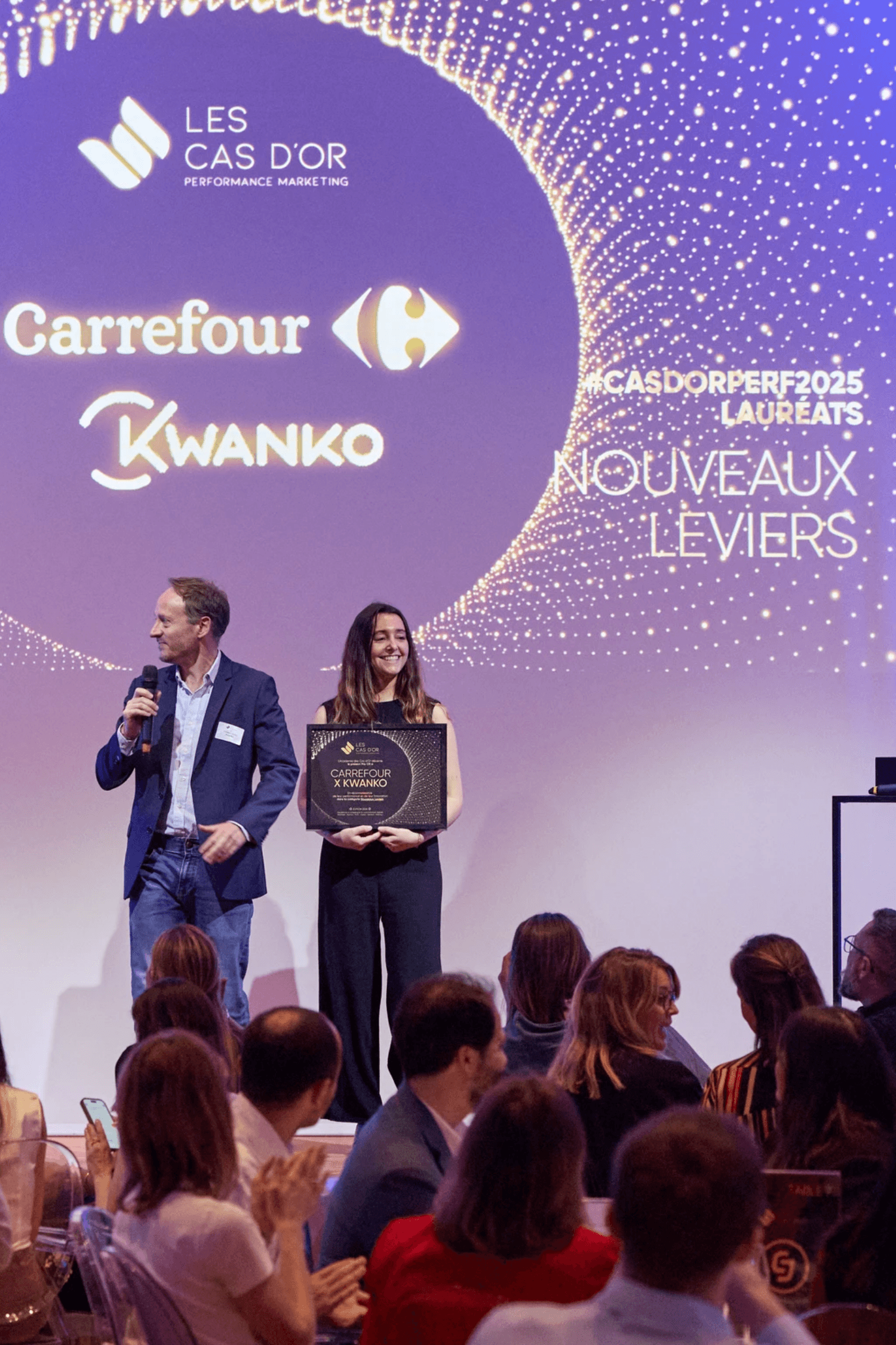 Person in a dark shirton a phone call, seated at a desk with papers, exudes a thoughtful, focused demeanor. Background shows dark horizontal blinds.