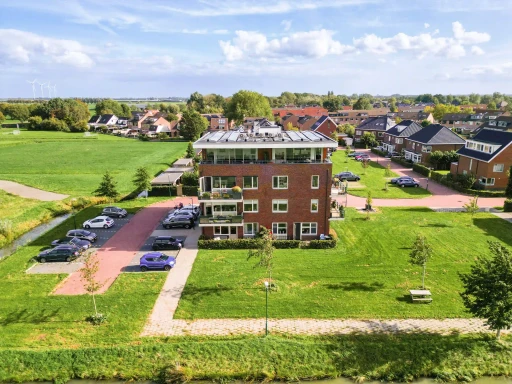 Een luchtfoto van het appartementencomplex met het omliggende grasveld en de parkeerplaatsen.