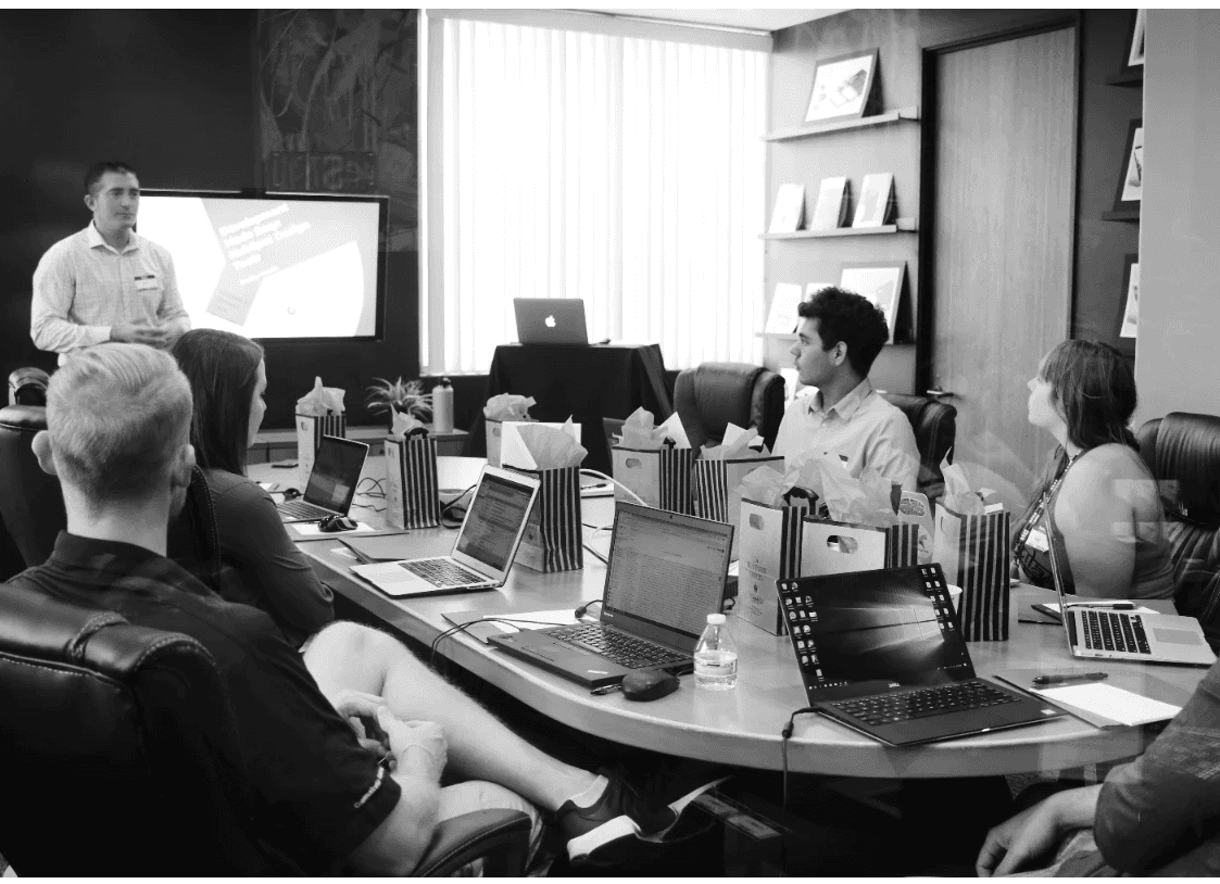 man standing in front of people sitting beside table with laptop computers