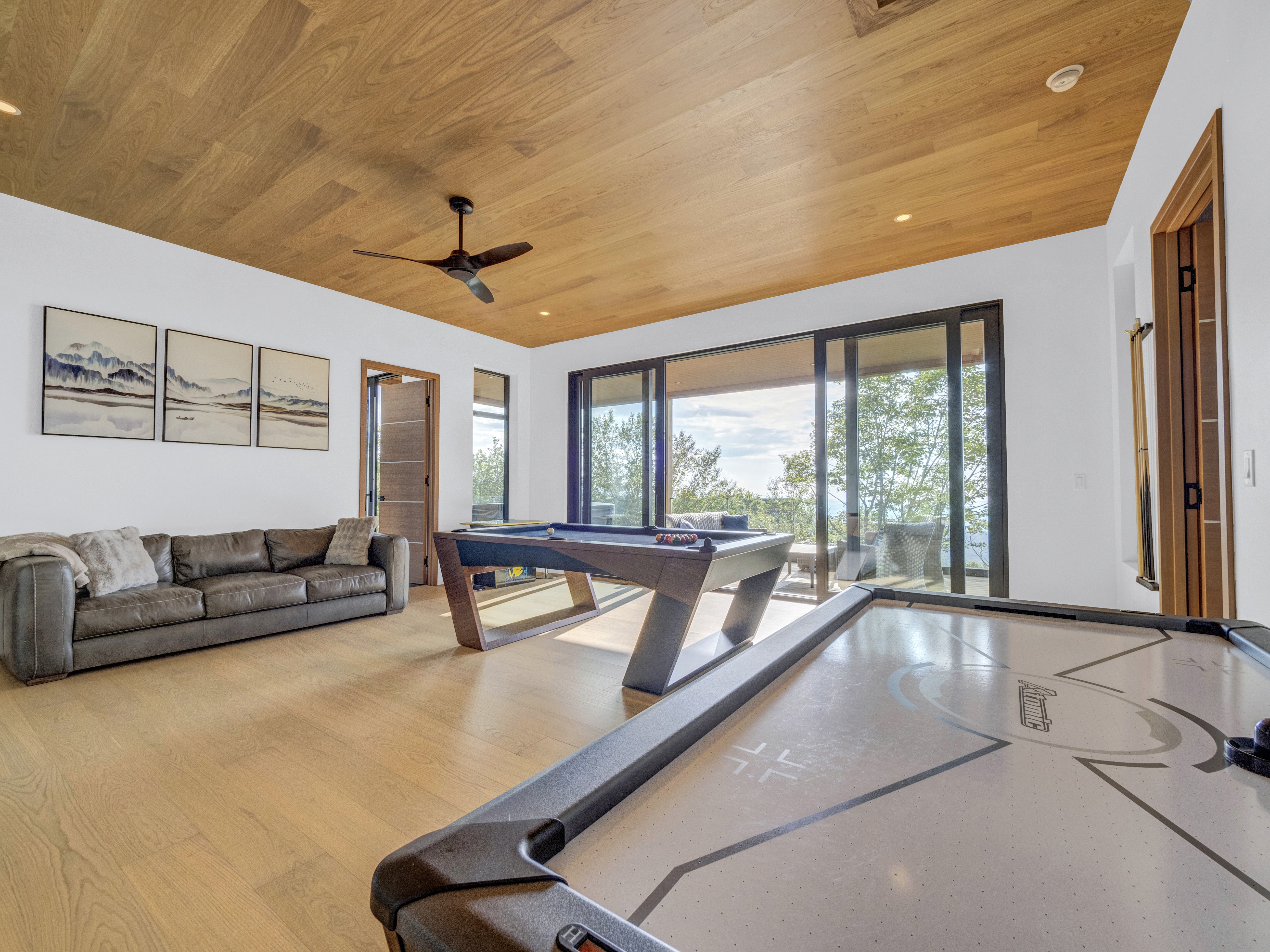 An outdoor children's obstacle course with colorful hanging rings and a swing set in a wooded backyard next to a modern cabin