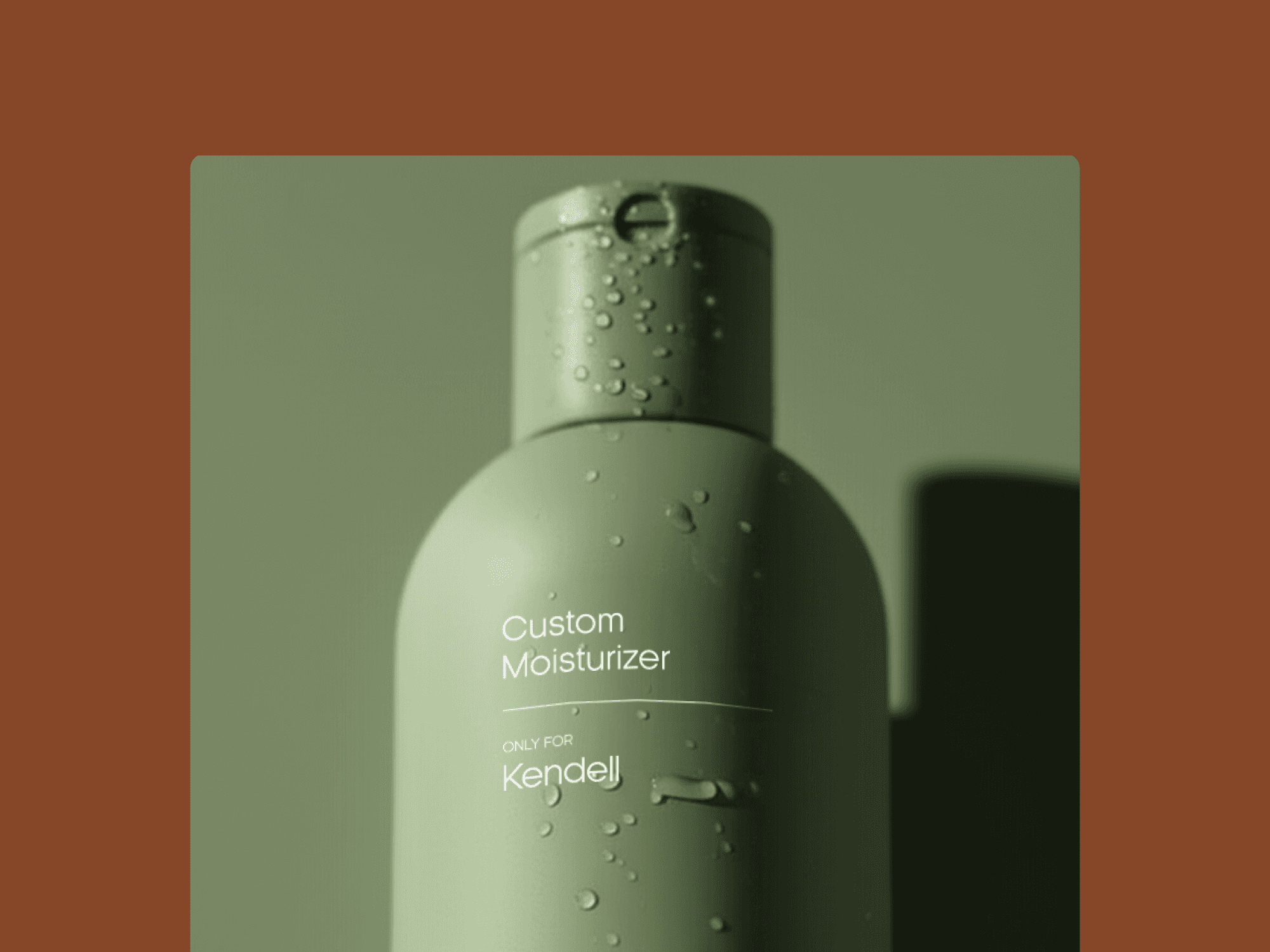 A close-up, high-detail shot of a matte olive green moisturizer bottle for "She's The One." The bottle is covered in clear, fresh water droplets, emphasizing hydration. Minimalist white text on the front reads "Custom Moisturizer" and "ONLY FOR Kendell." The product is set against a soft sage green background and framed by a rich terracotta border, creating a calm, earthy color story.