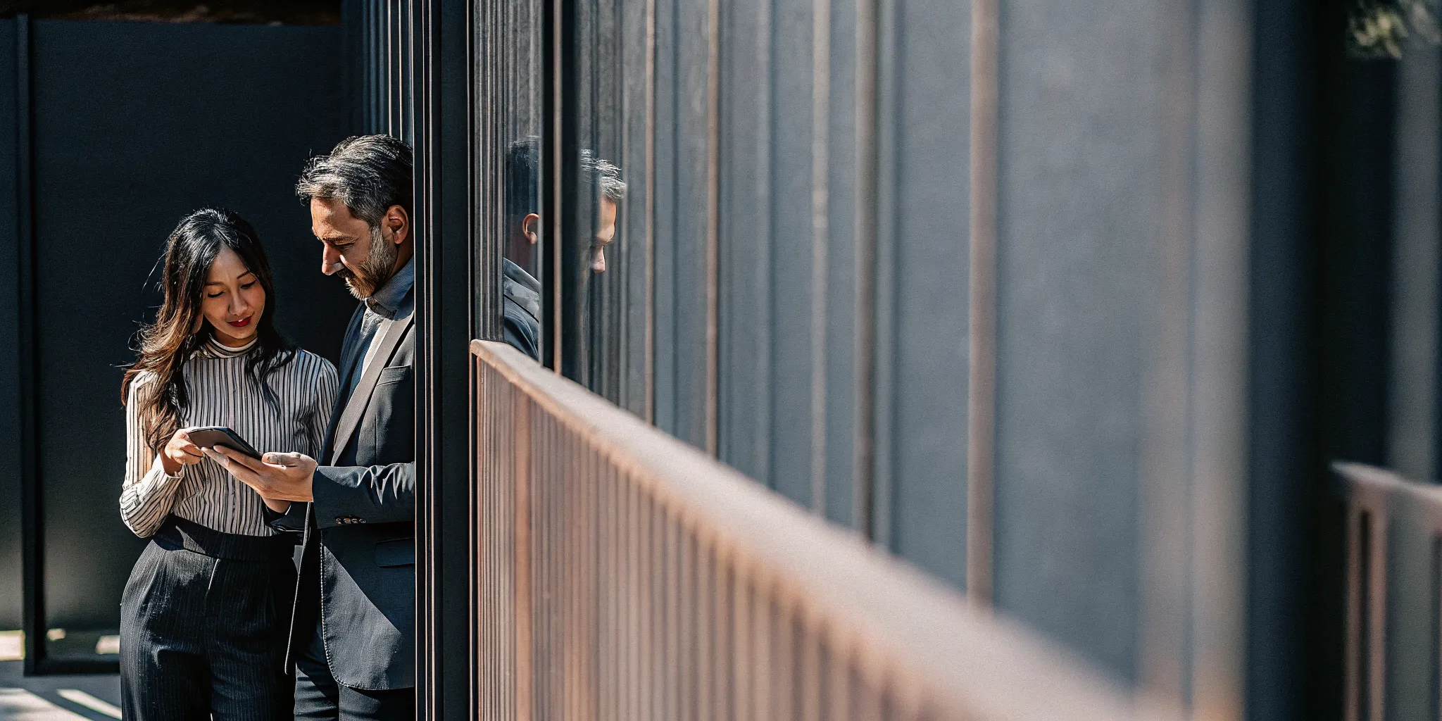 Two audit directors collaborating beside a glass wall with a digital evidence workflow in the background