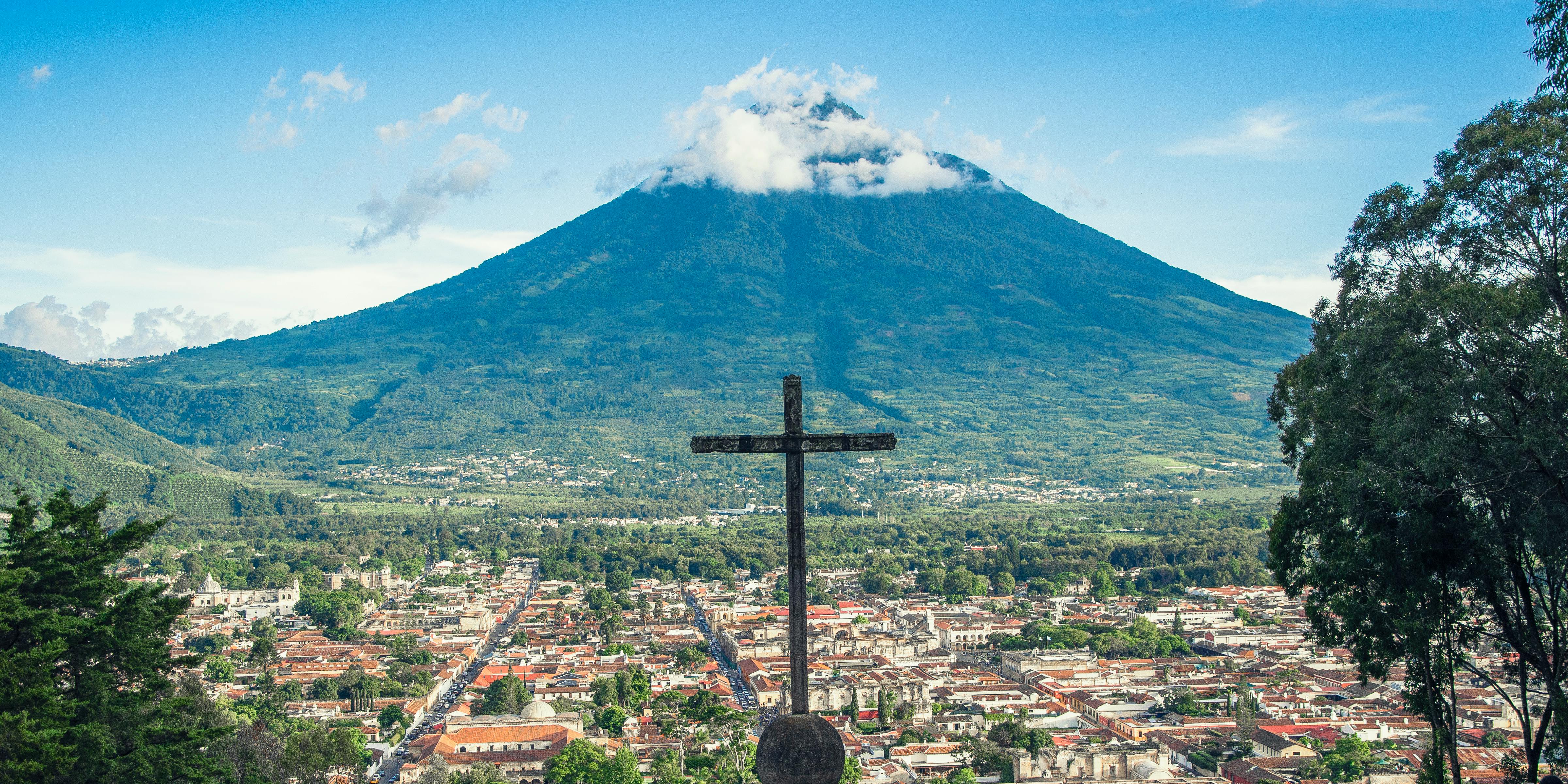 A cross on top of a building with a mountain in the background