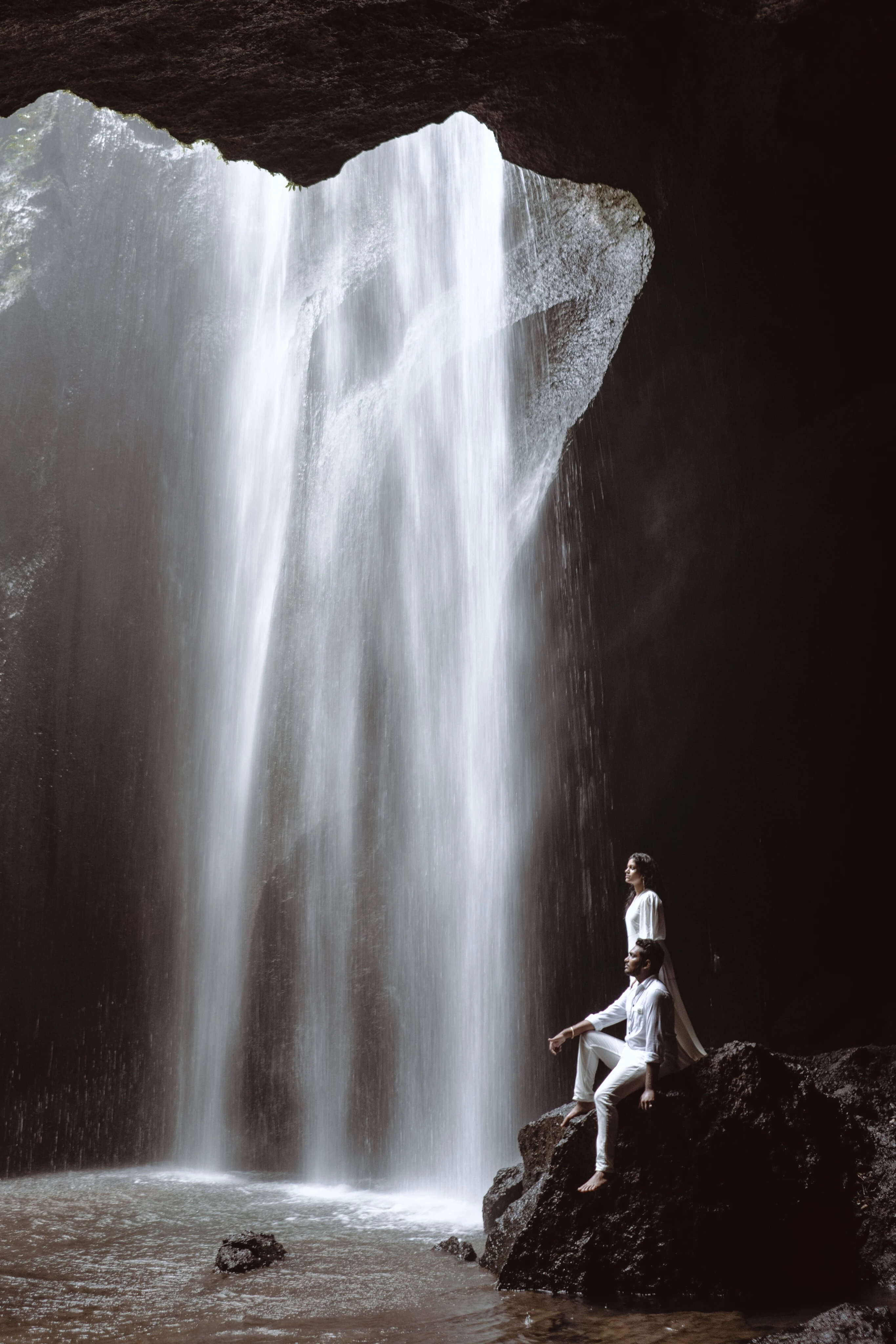 Lovely & Rohit share a serene moment at the edge of a breathtaking waterfall, surrounded by lush nature – captured by Out of The Blues, Fine Art Wedding Photography in Hyderabad.