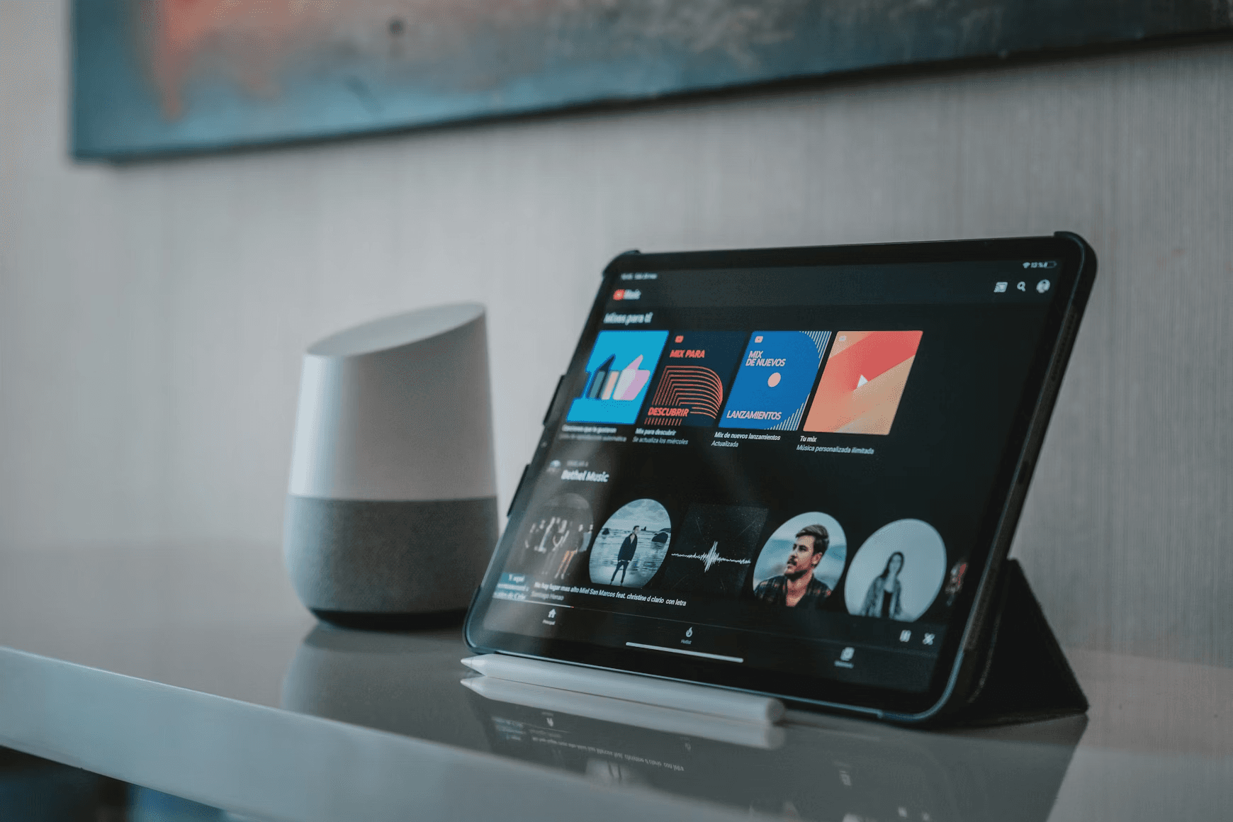 Tablet displaying music app next to smart speaker.