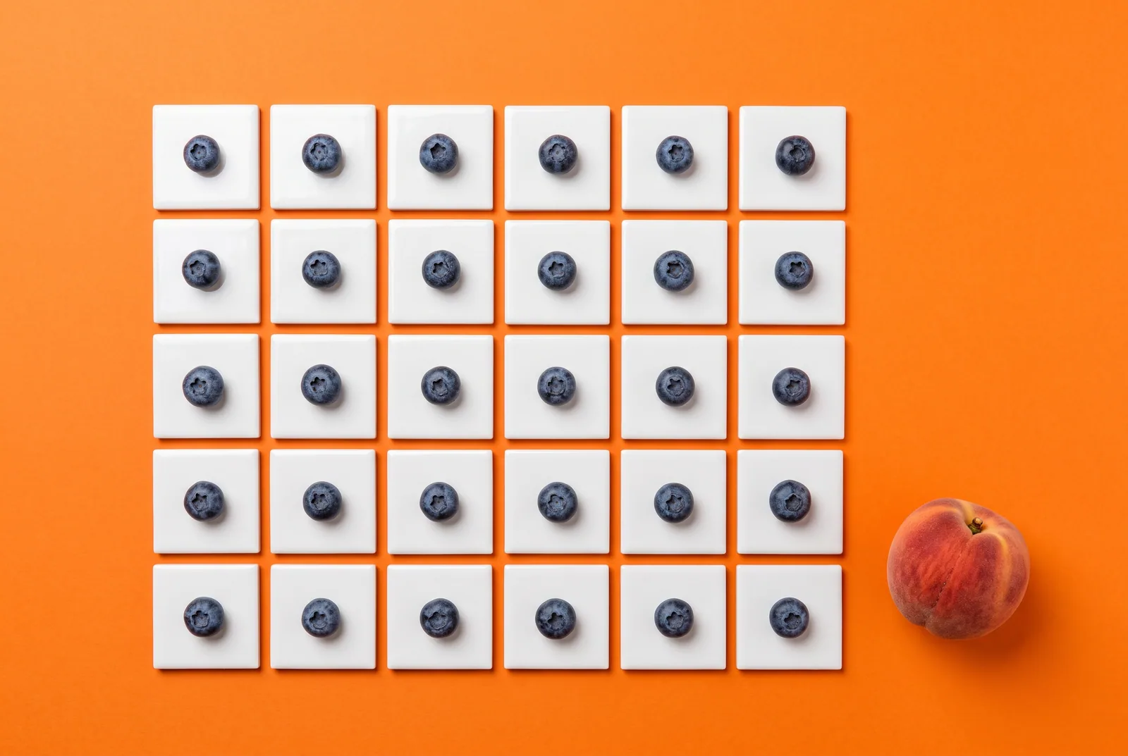 Thirty white tiles each holding a blueberry with a peach set aside, a 30-day plan to quit OnlyFans addiction
