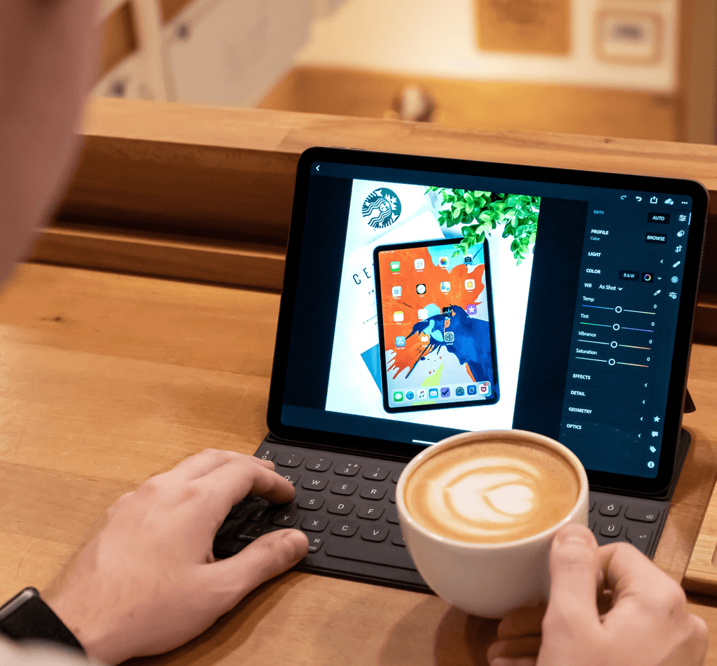 A person touching a computer holding a cup of coffee