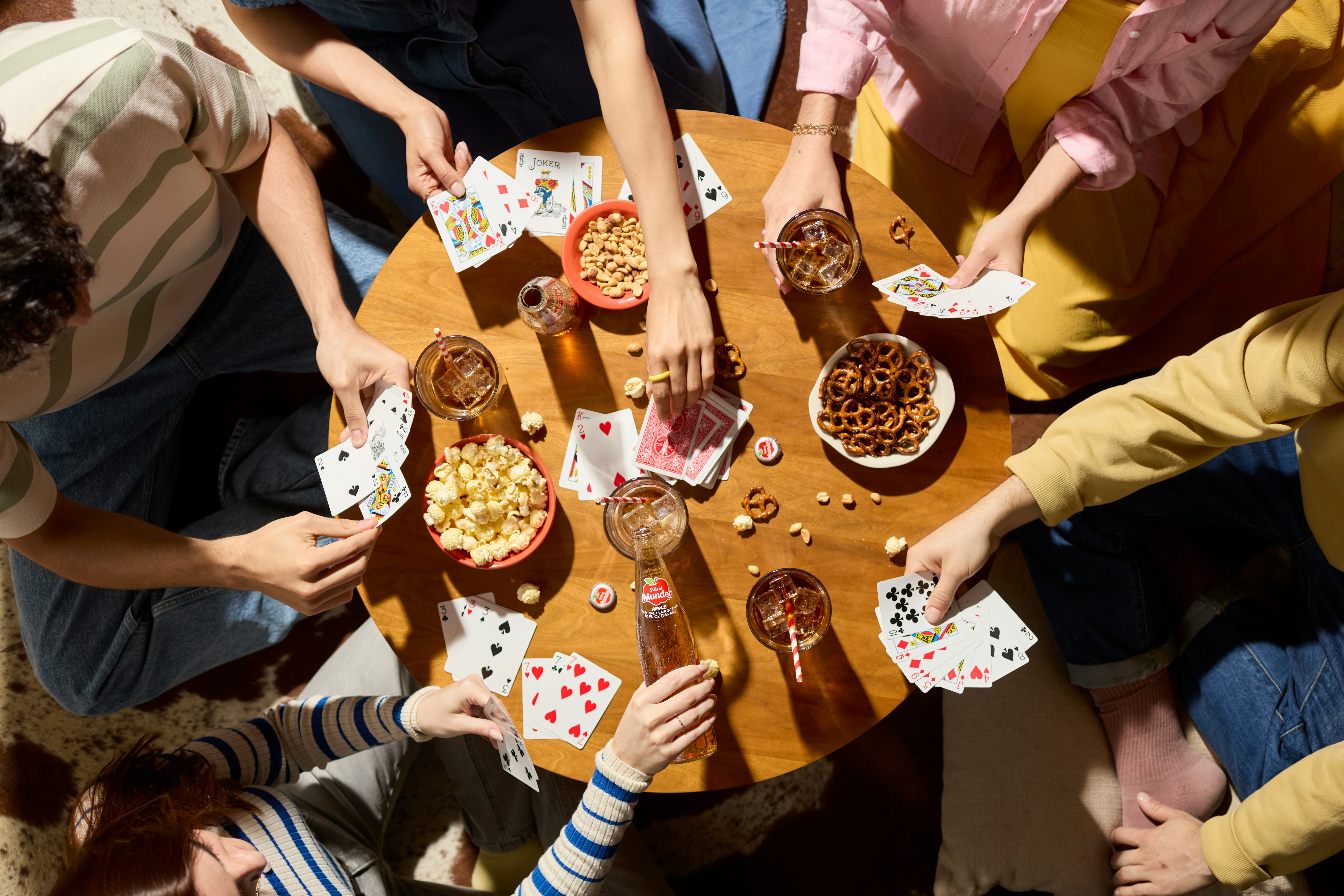 Friends play cards, sharing snacks and drinks.