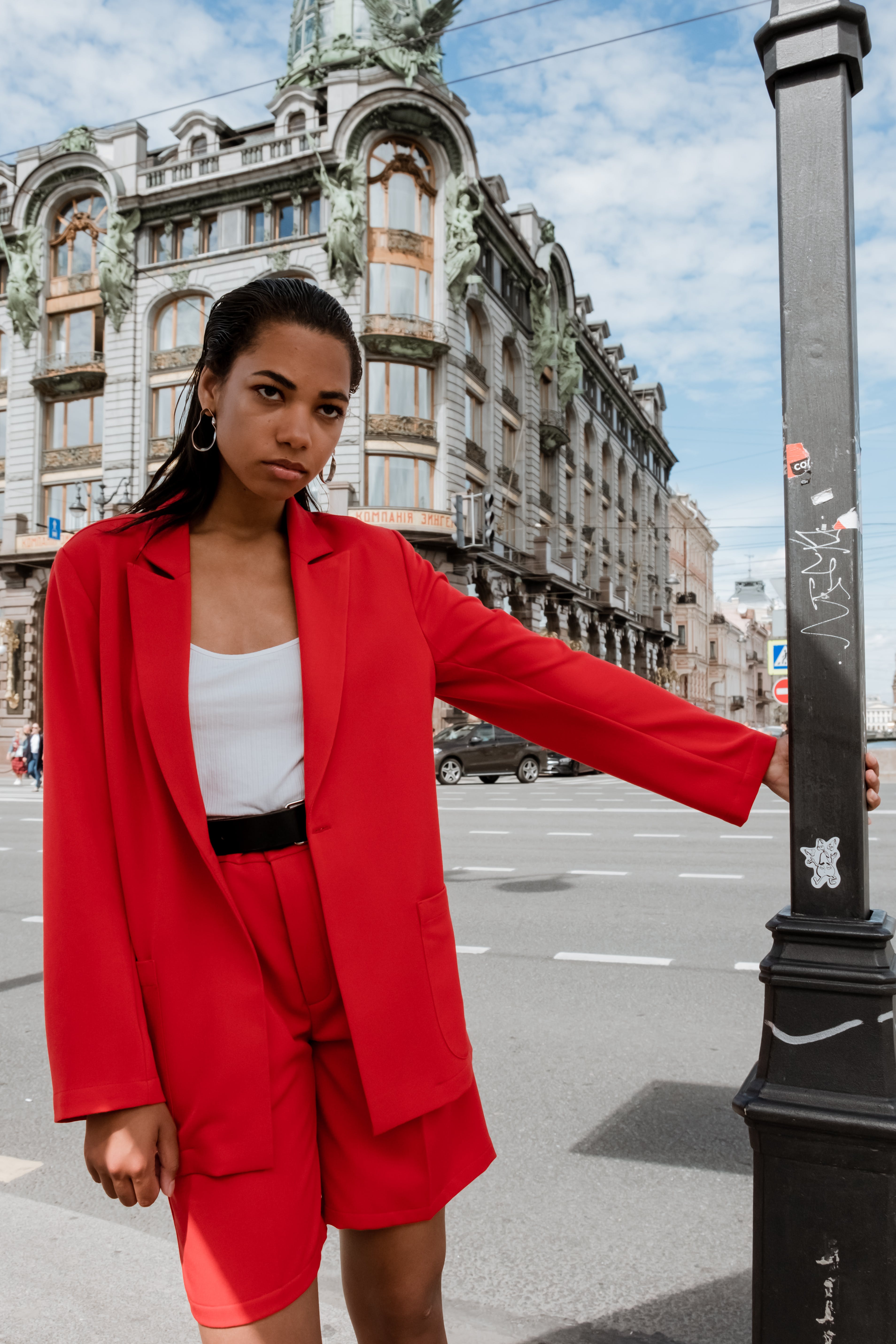 a woman in red dress holding a post in a road