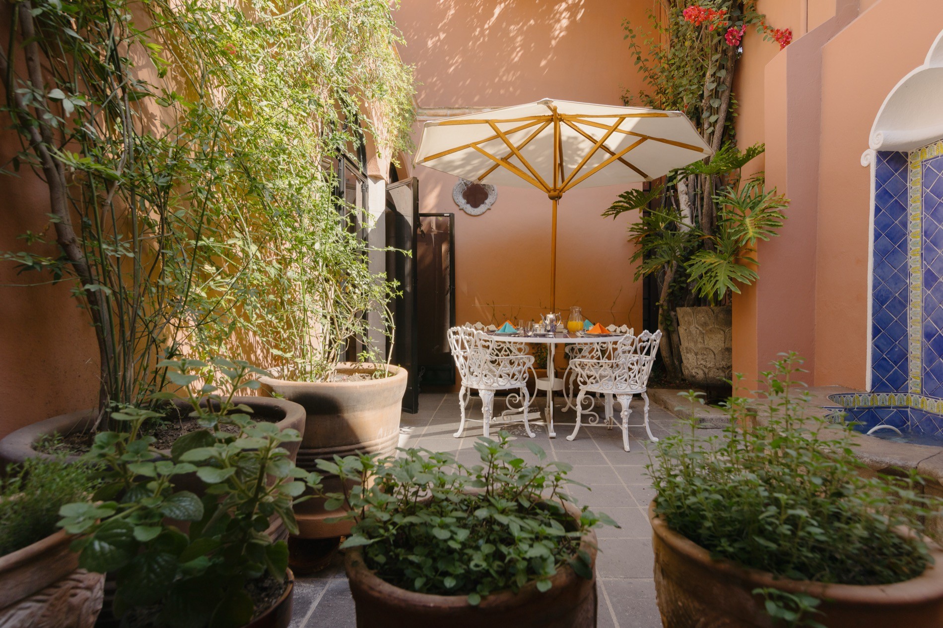 La Residencia San Miguel outdoor dining area in secluded garden with wall fountain and greenery