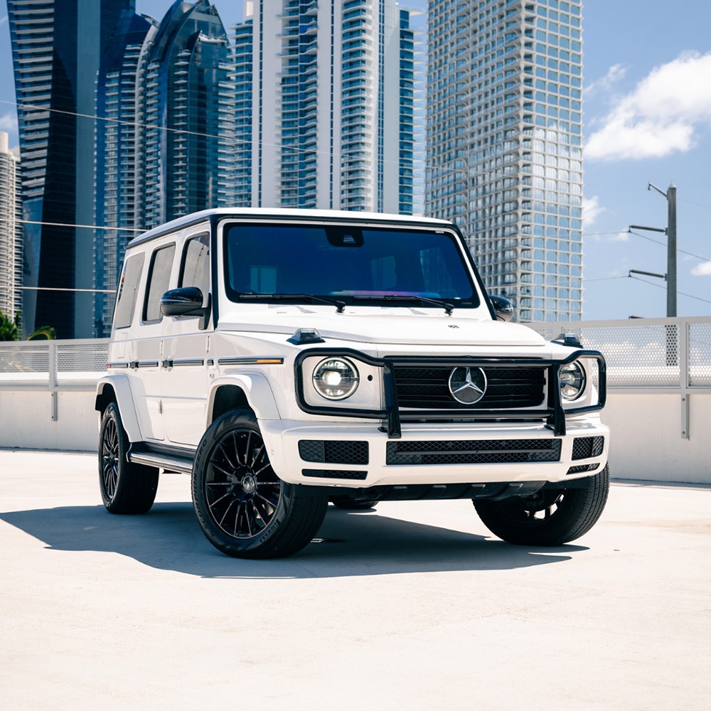 Front 3/4 view of a white Mercedes-Benz G 550 (G-Wagon) rental in Miami, showcasing its iconic boxy design.