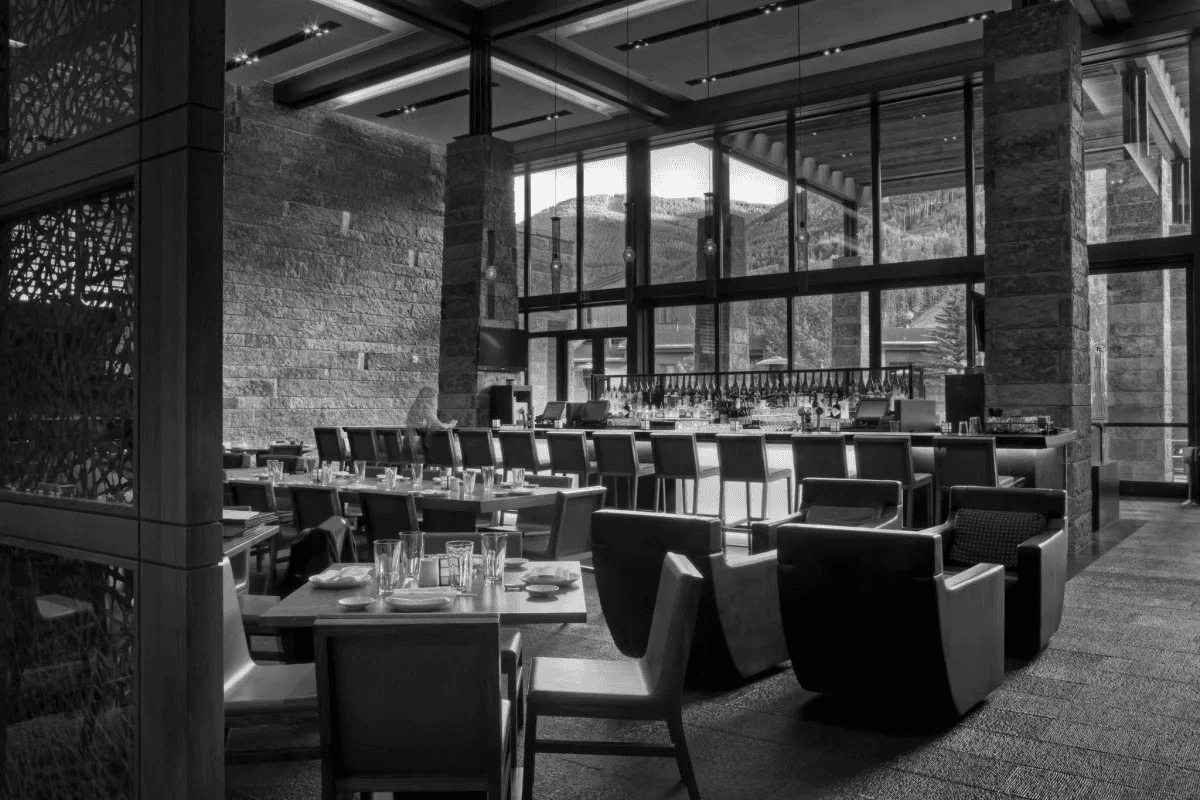 Black and white image of people working at a table with laptops, showing hands gesturing during discussion of digital content displayed on screens, with fabrica® logo in the corner.