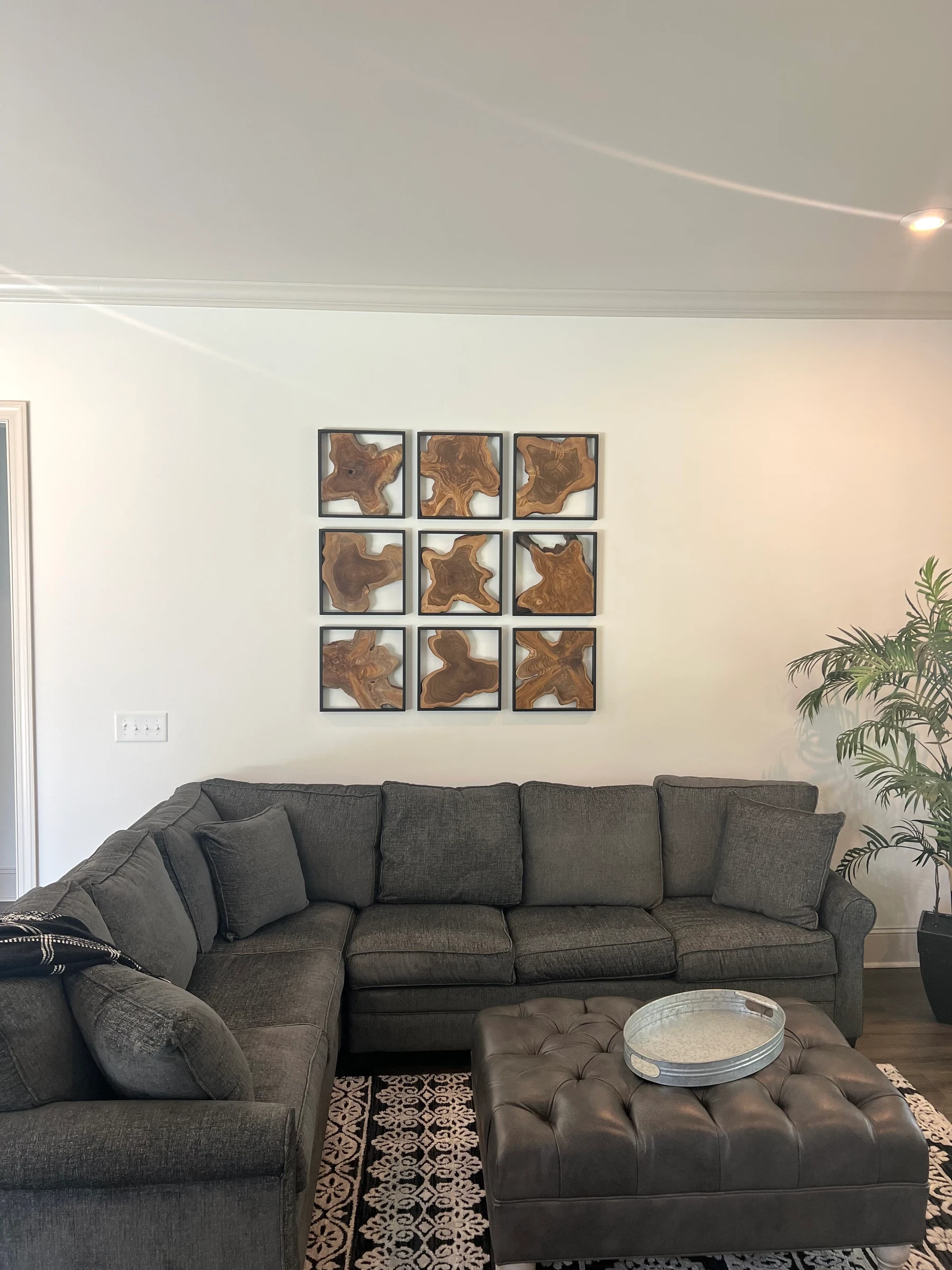 Nine framed artworks arranged in three rows and three columns above a gray sectional.