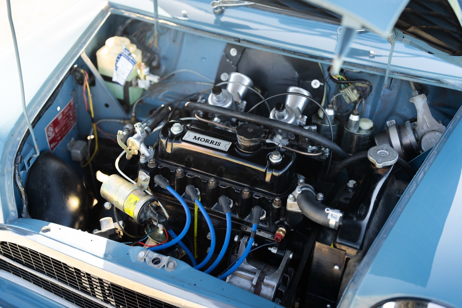 Close-up of a blue car engine, showcasing various components and wiring in detail.