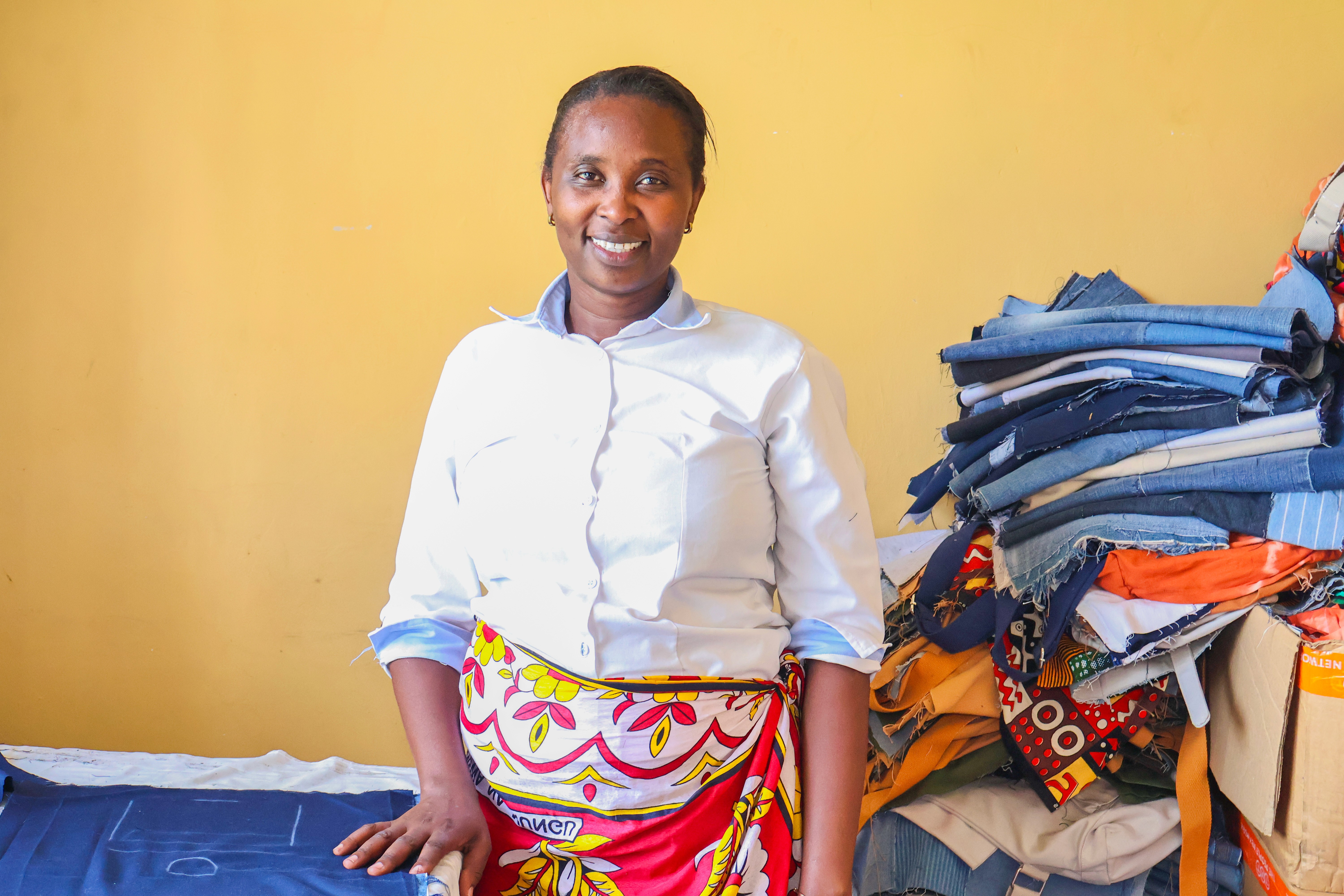 Woman smiling while standing at a table with fabric marked for tailoring.