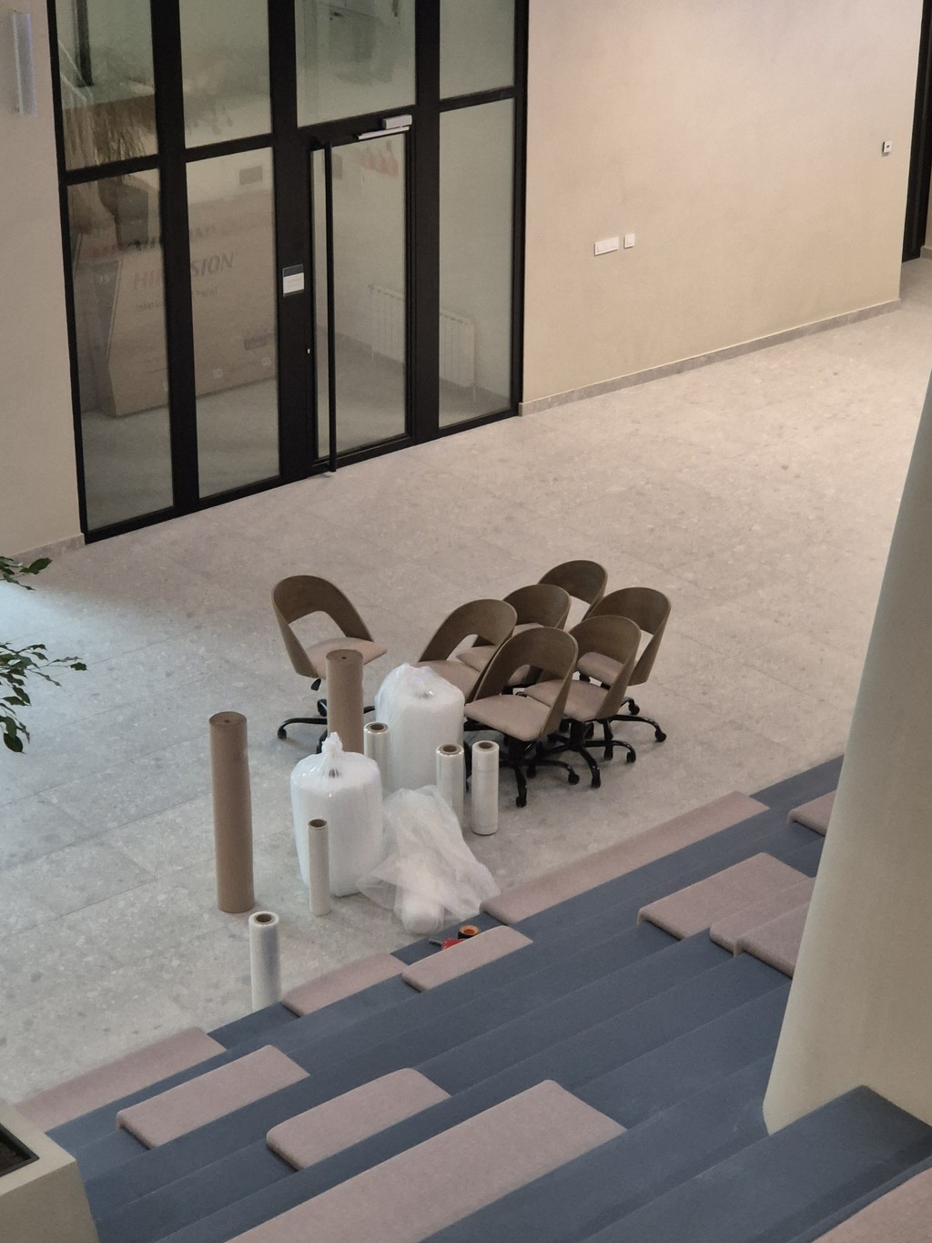 Unutrašnjost modernog poslovnog prostora sa kancelarijskim stolicama i zaštitno upakovanim nameštajem spremnim za selidbu