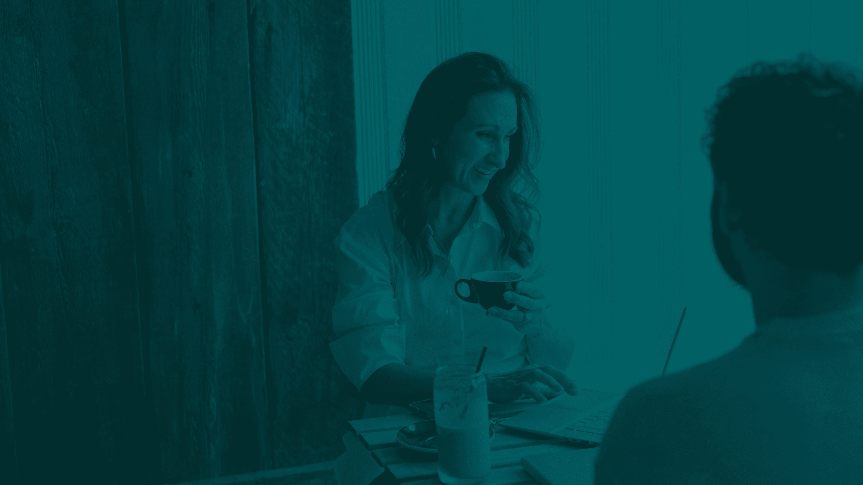 Stacy holding a glass, while talking to a person facing her.