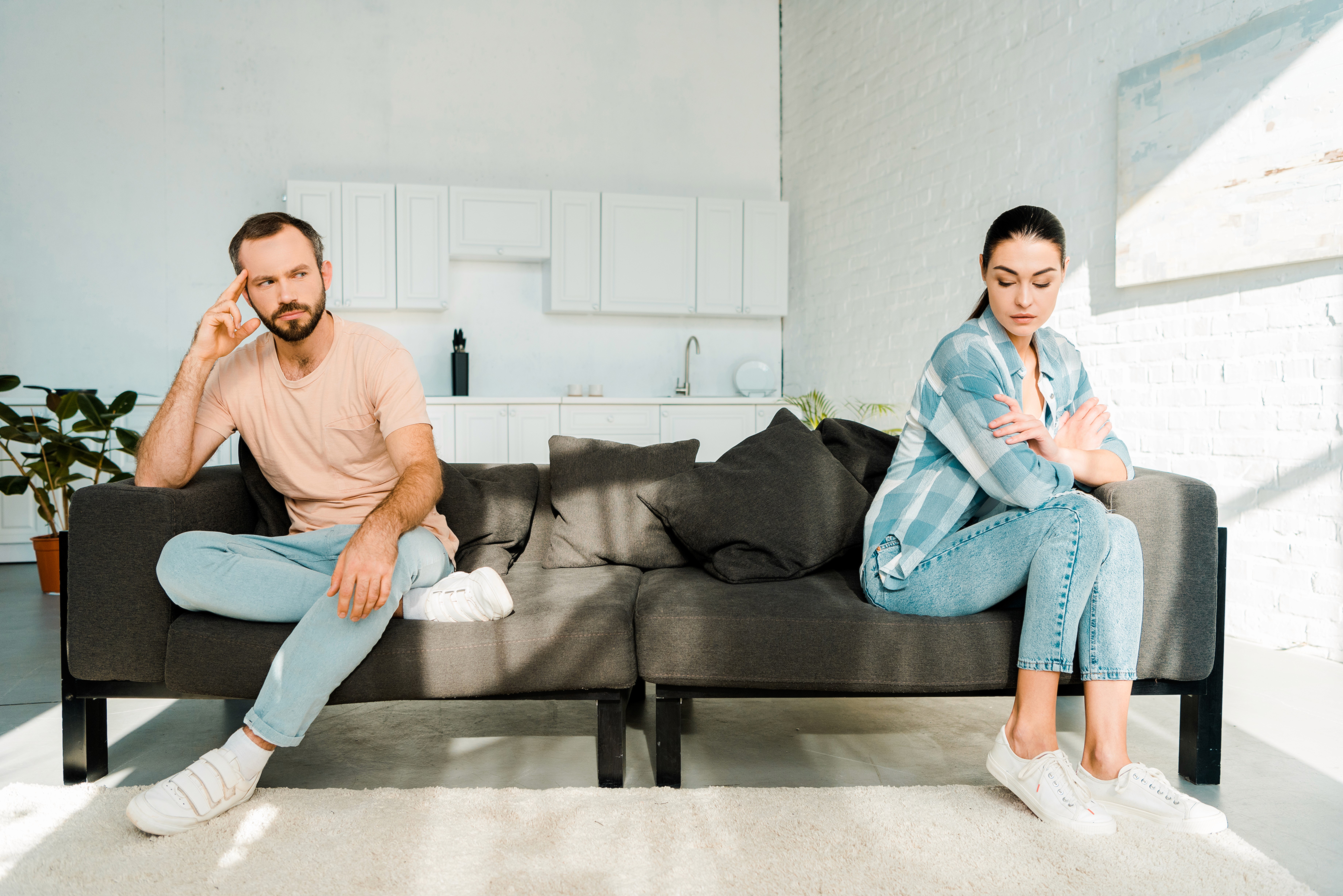 Couple sitting apart on a couch looking tense and disconnected, representing common misconceptions about family law and divorce that Essex County residents face before consulting an attorney