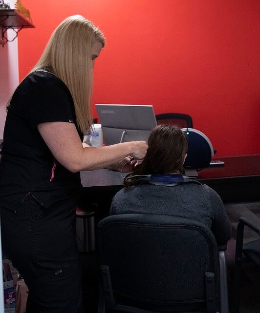 A close-up of a person receiving an ear cleaning, with hands gently handling their ear.