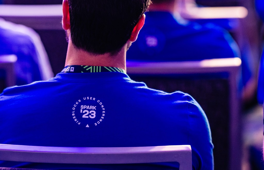 Photo of the back of a man wearing a SPARK tshirt and lanyard. 