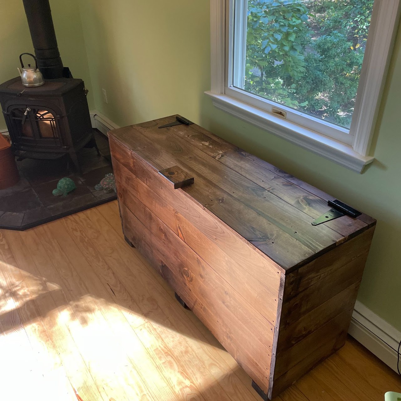 Custom stained pine chest with iron hardware below bright window