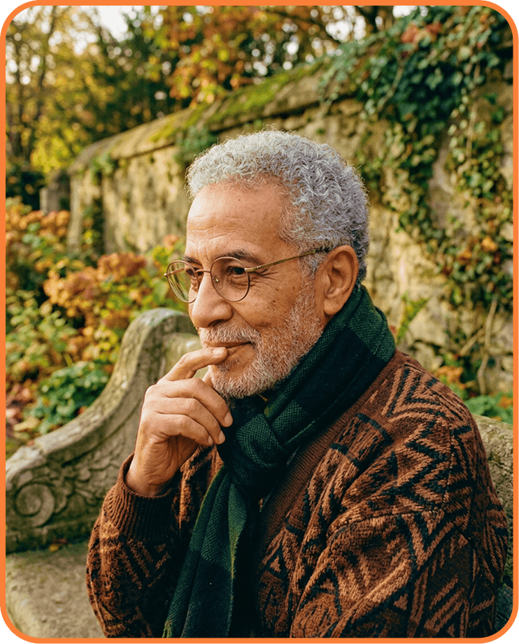 Older man with glasses sitting  in a garden