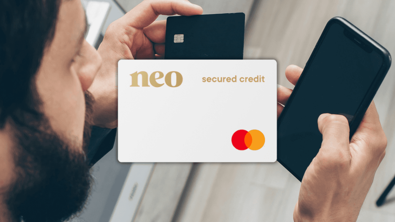 A newcomer in Canada checking his mobile banking app and credit score on a smartphone while holding a secured credit card.