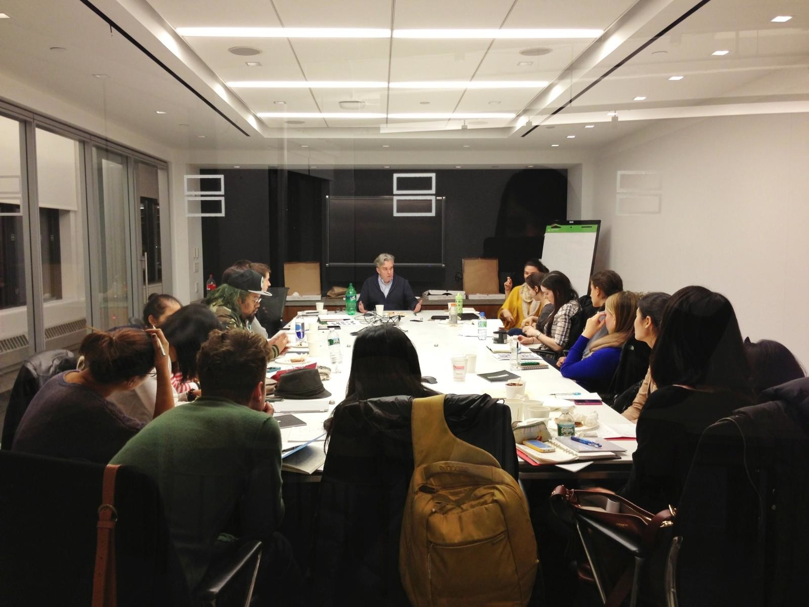 A photo of a group of people listening to a lecture while sitting at a conference table.