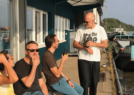 Vier Personen sitzen auf dem Steg vor dem Ponton von Design for Human Nature in Entenwerder uns tauschen sich aus.