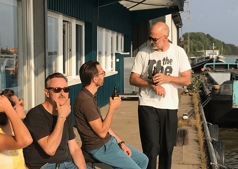 Vier Personen sitzen auf dem Steg vor dem Ponton von Design for Human Nature in Entenwerder uns tauschen sich aus.