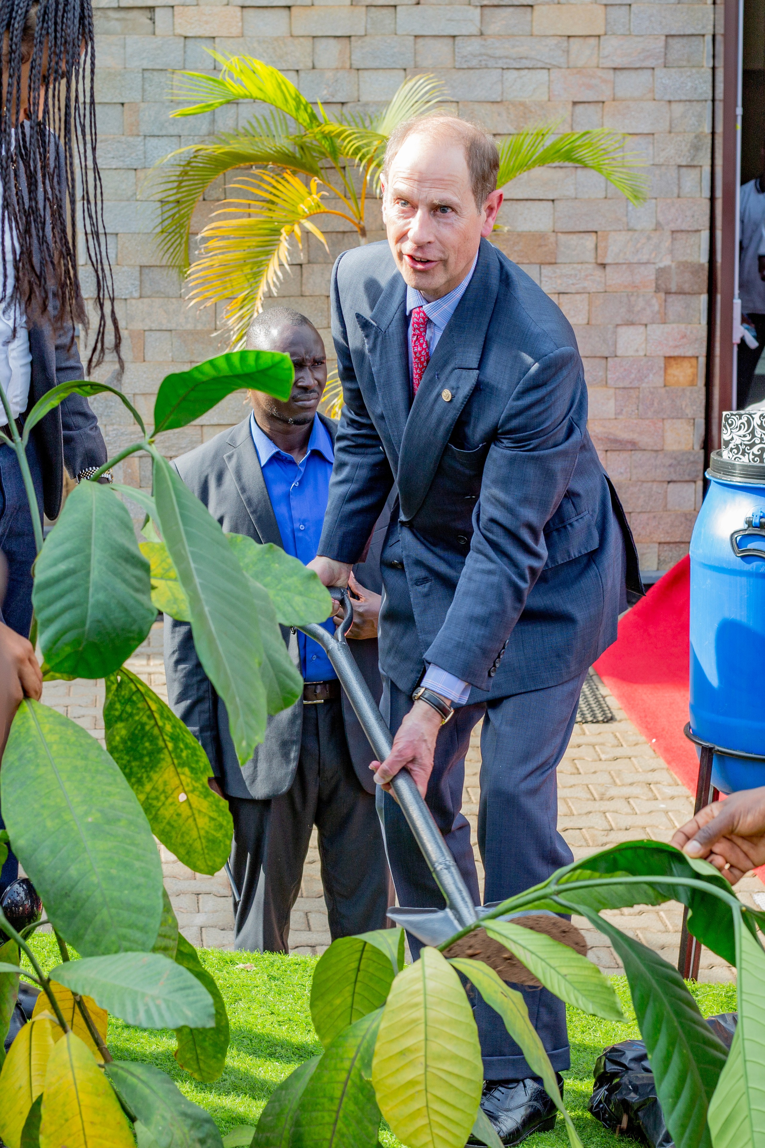 A student wearing a red uniform sits while holding a book in his hands