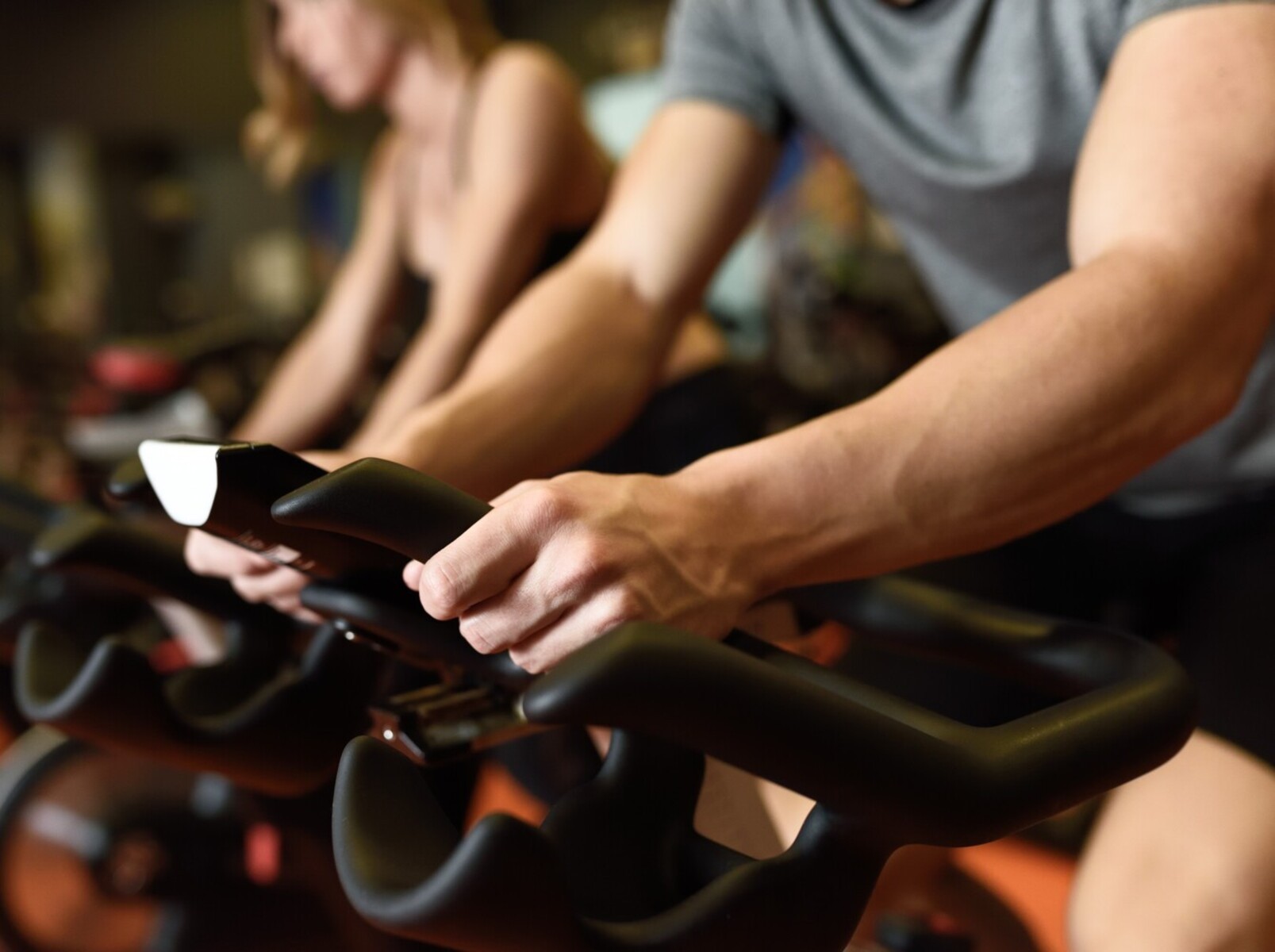 closeup of a couple doing a cycling for weight loss class at the gym
