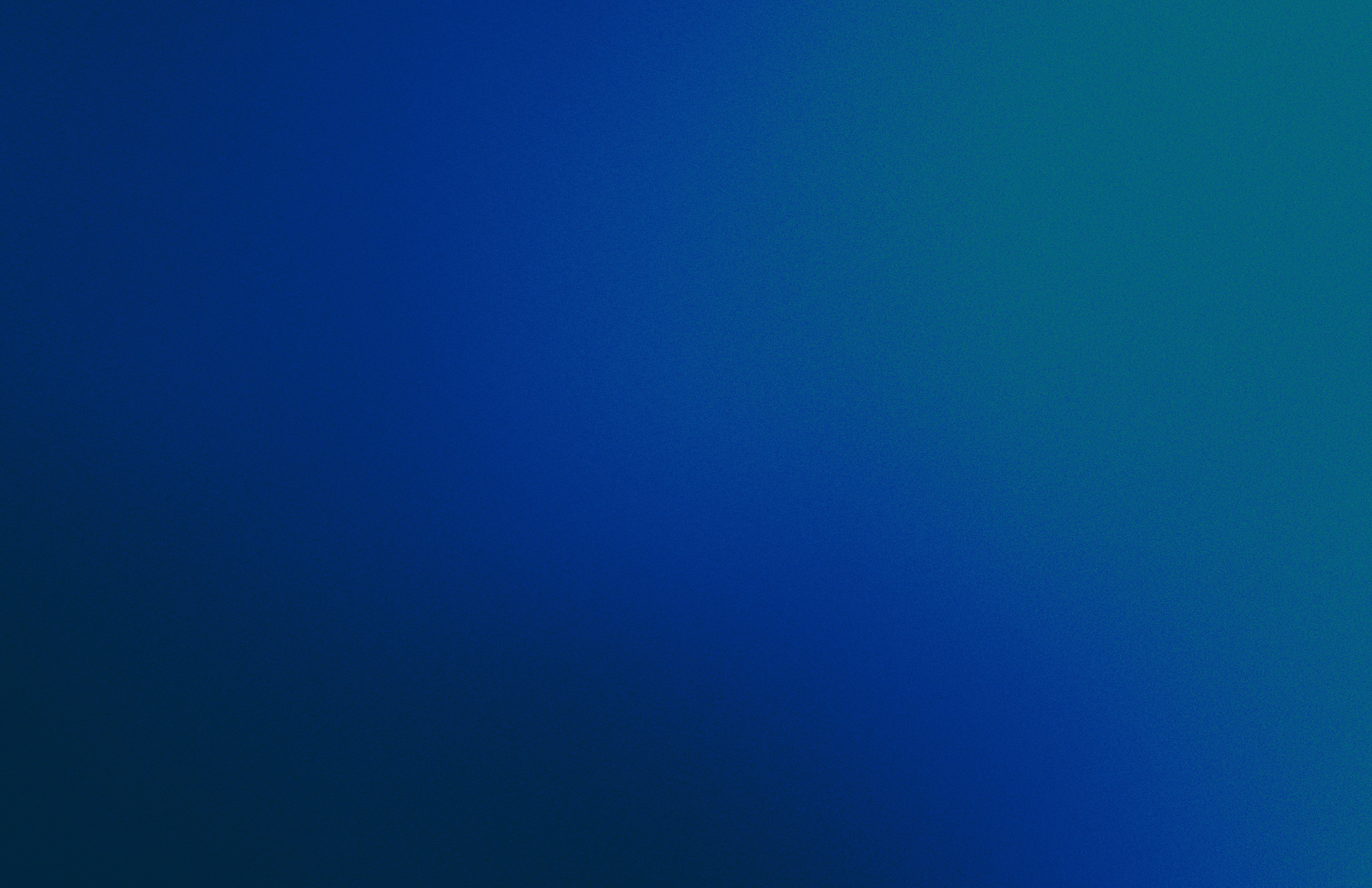 A man stands while two people sit at a table in an office setting, smiling and engaged in conversation. The mood is friendly and collaborative.