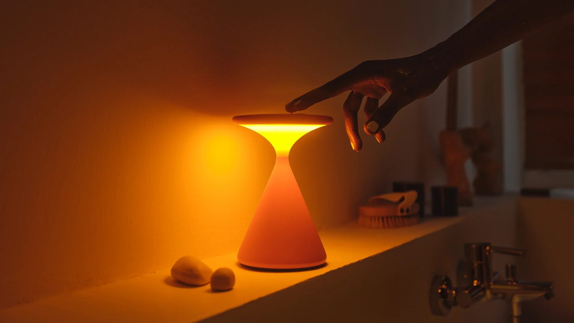 Hand touching the top of modern table lamp on shelf