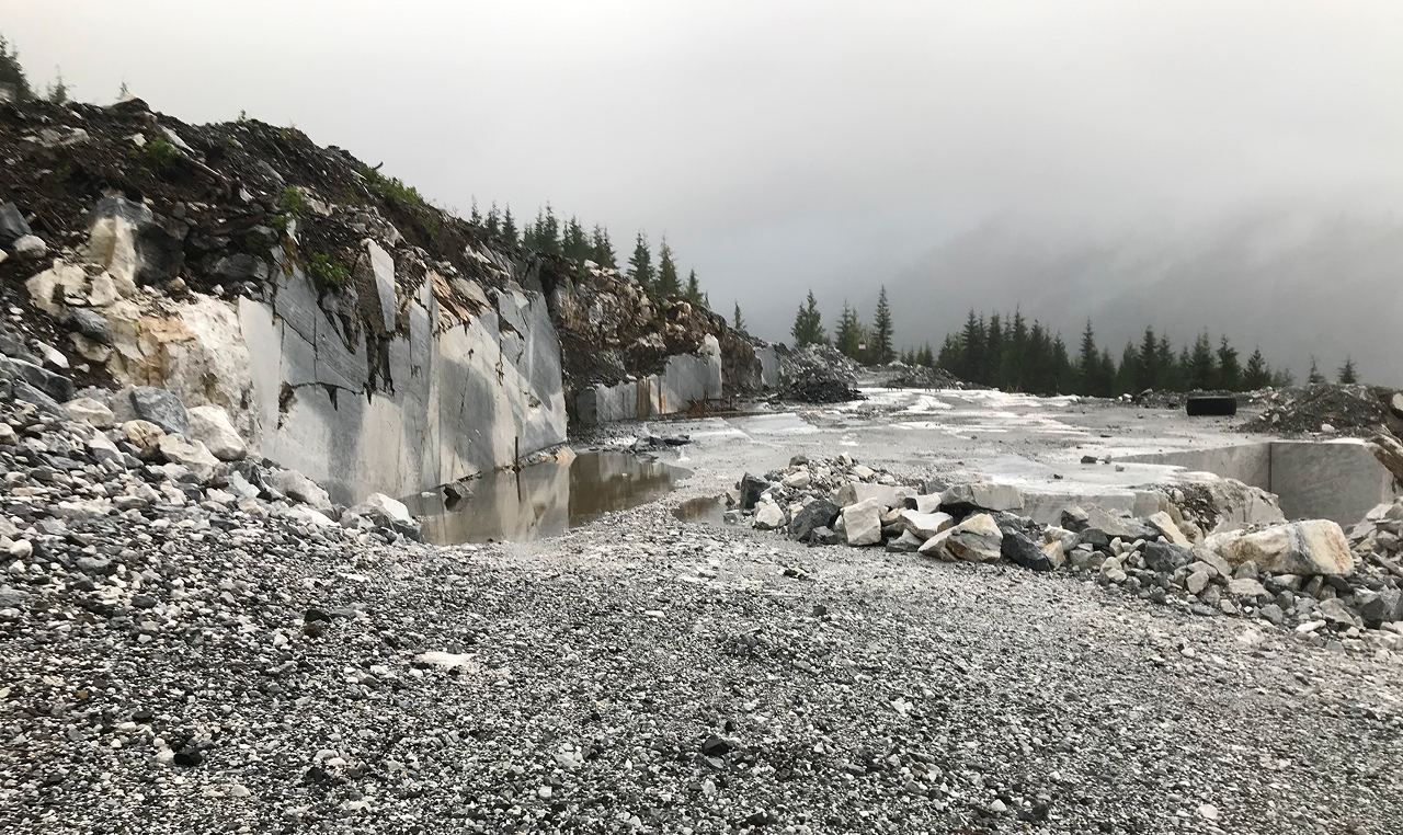 Flooded quarry pit with exposed marble walls and scattered stone debris at Callache Quarry