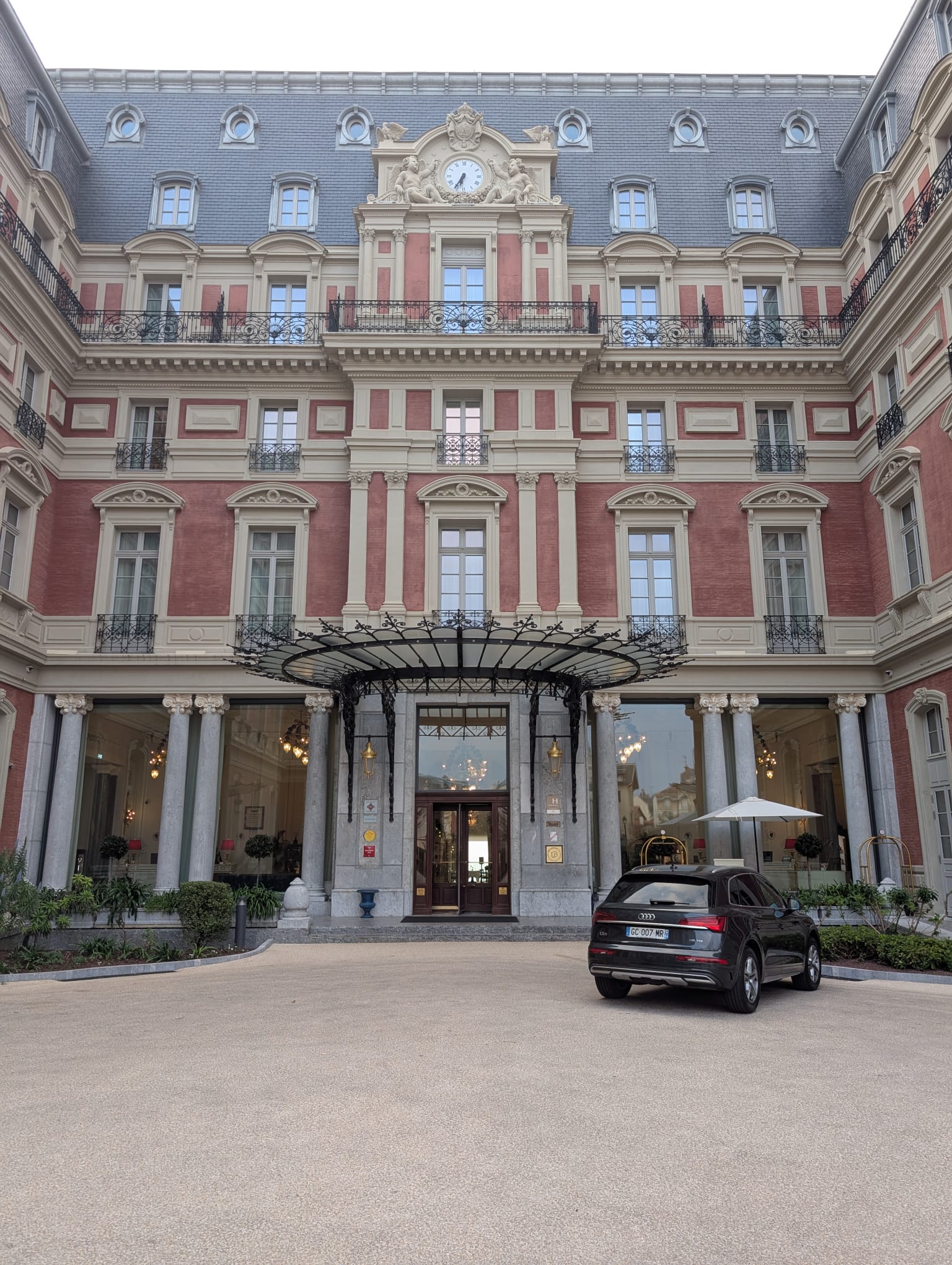 A bustling deli counter with hanging cured meats and a staff member preparing orders behind the counter.