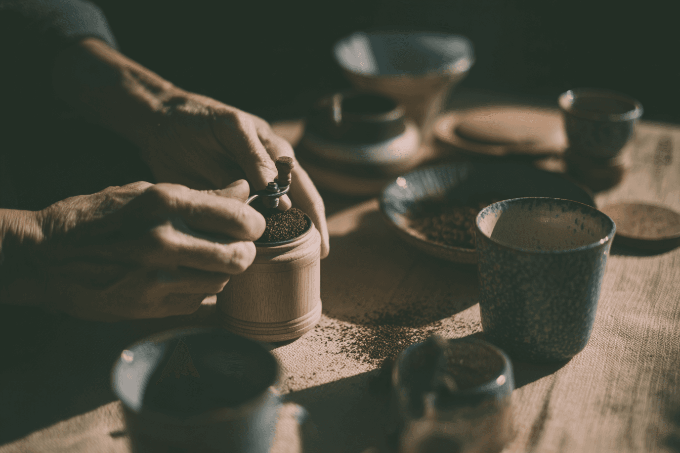 close-up of hands grinding coffee with wooden manual grinder