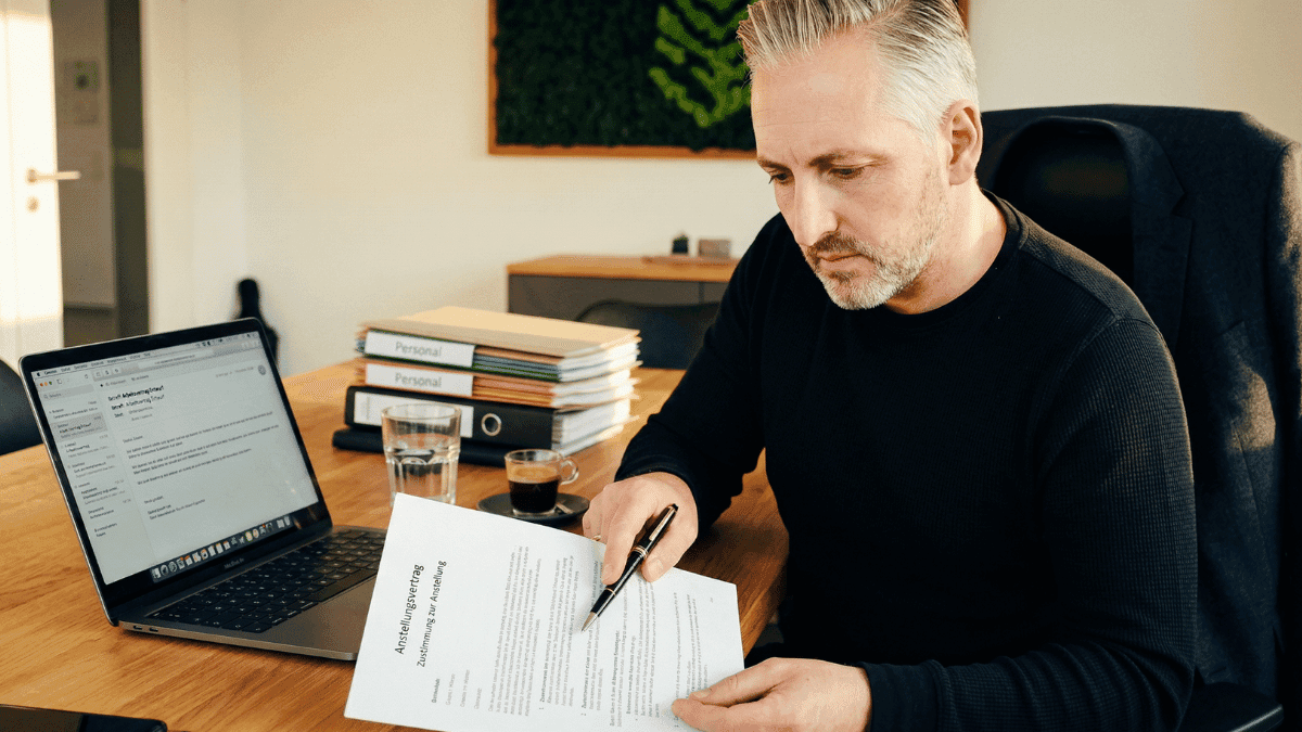 Arbeitgeber prüft Arbeitsvertrag auf Nachweisgesetz-Pflichtangaben am Schreibtisch