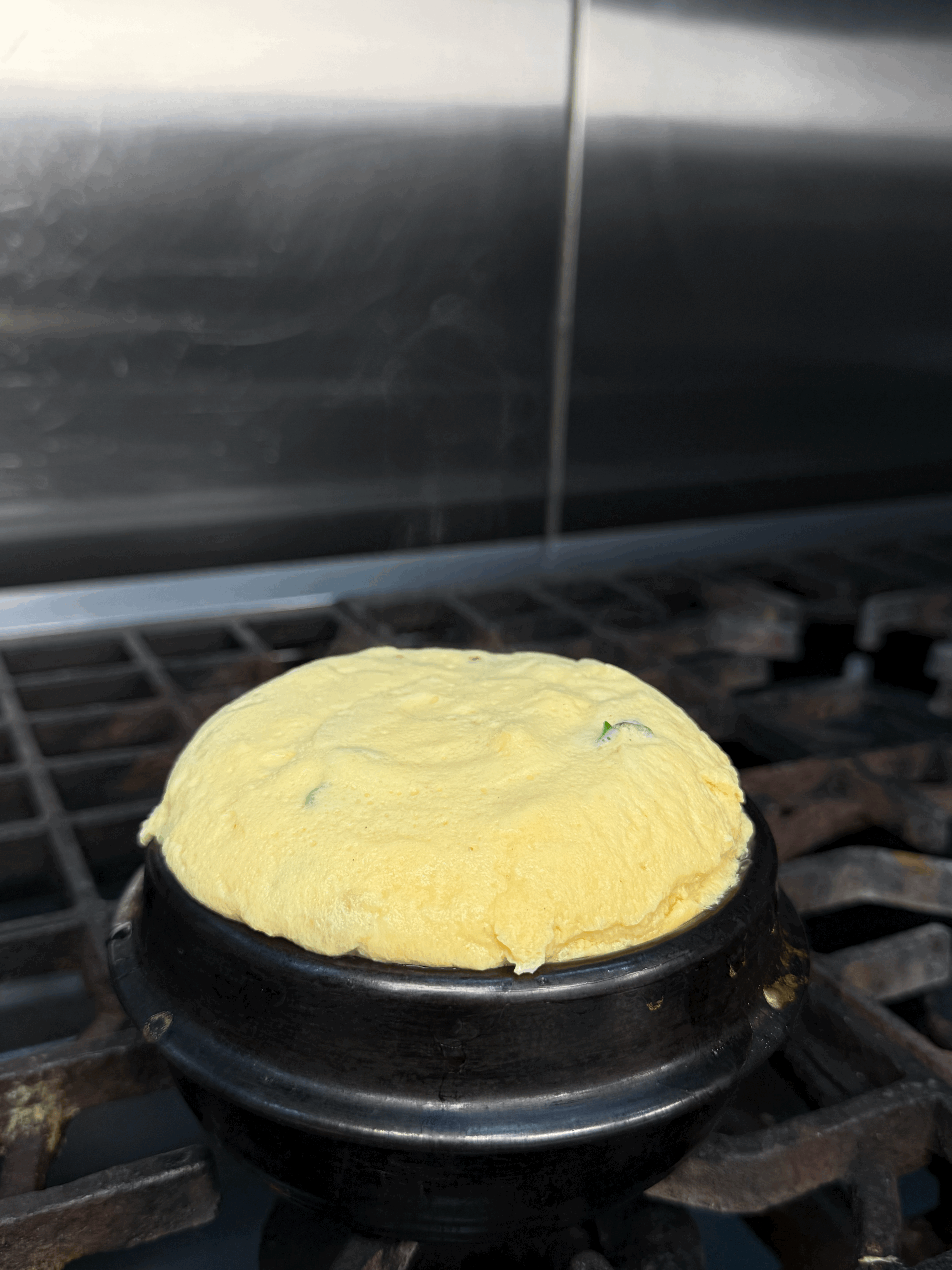 An overhead shot of a large oval plate featuring sliced, roasted duck, half glazed with a sauce, served over two thin pancakes and alongside steamed bok choy, surrounded by small bowls of condiments like scallions, sauce, salt, and carrot shreds.