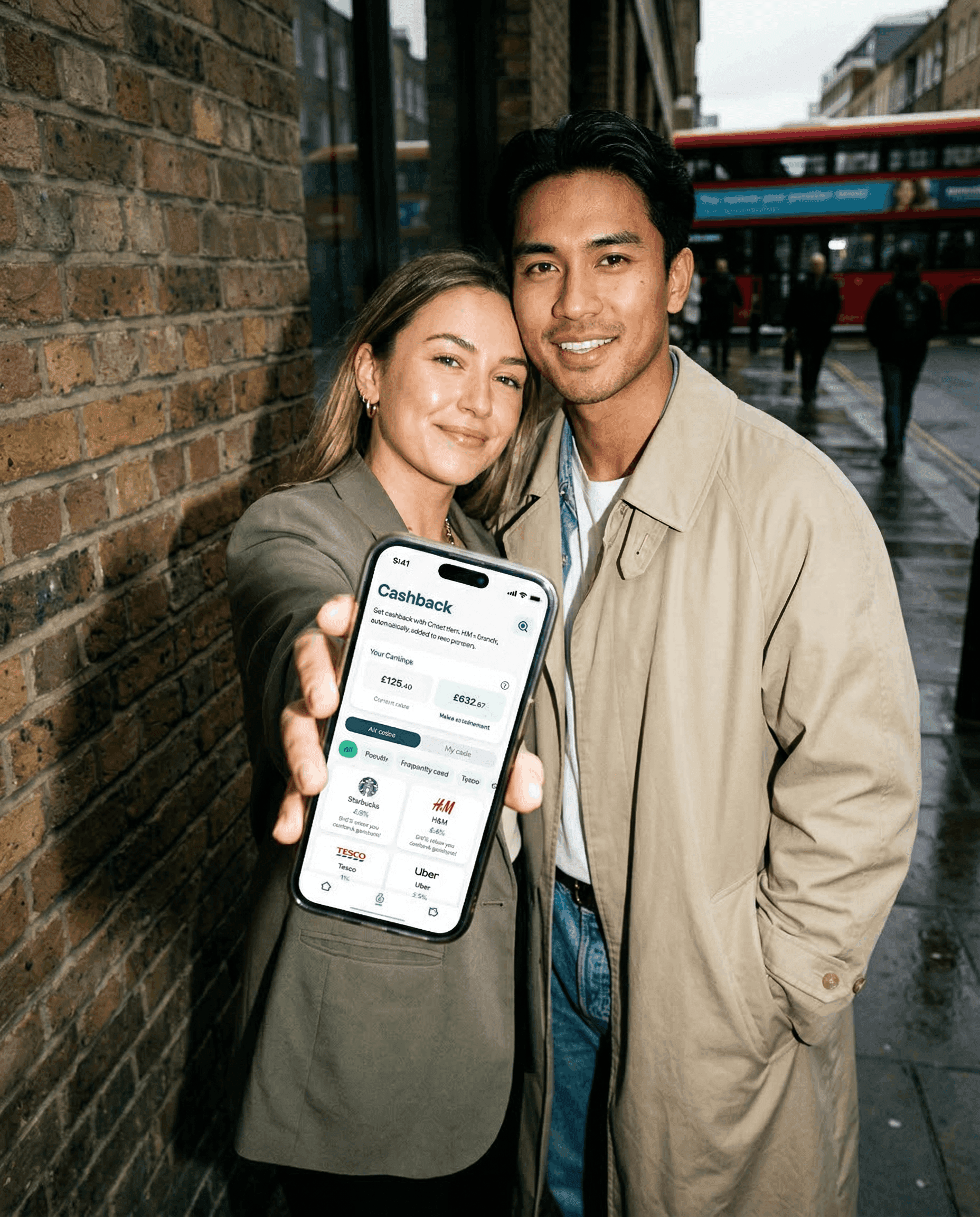 A young couple. The woman is holding out a phone showing the Chest pension app on her phone