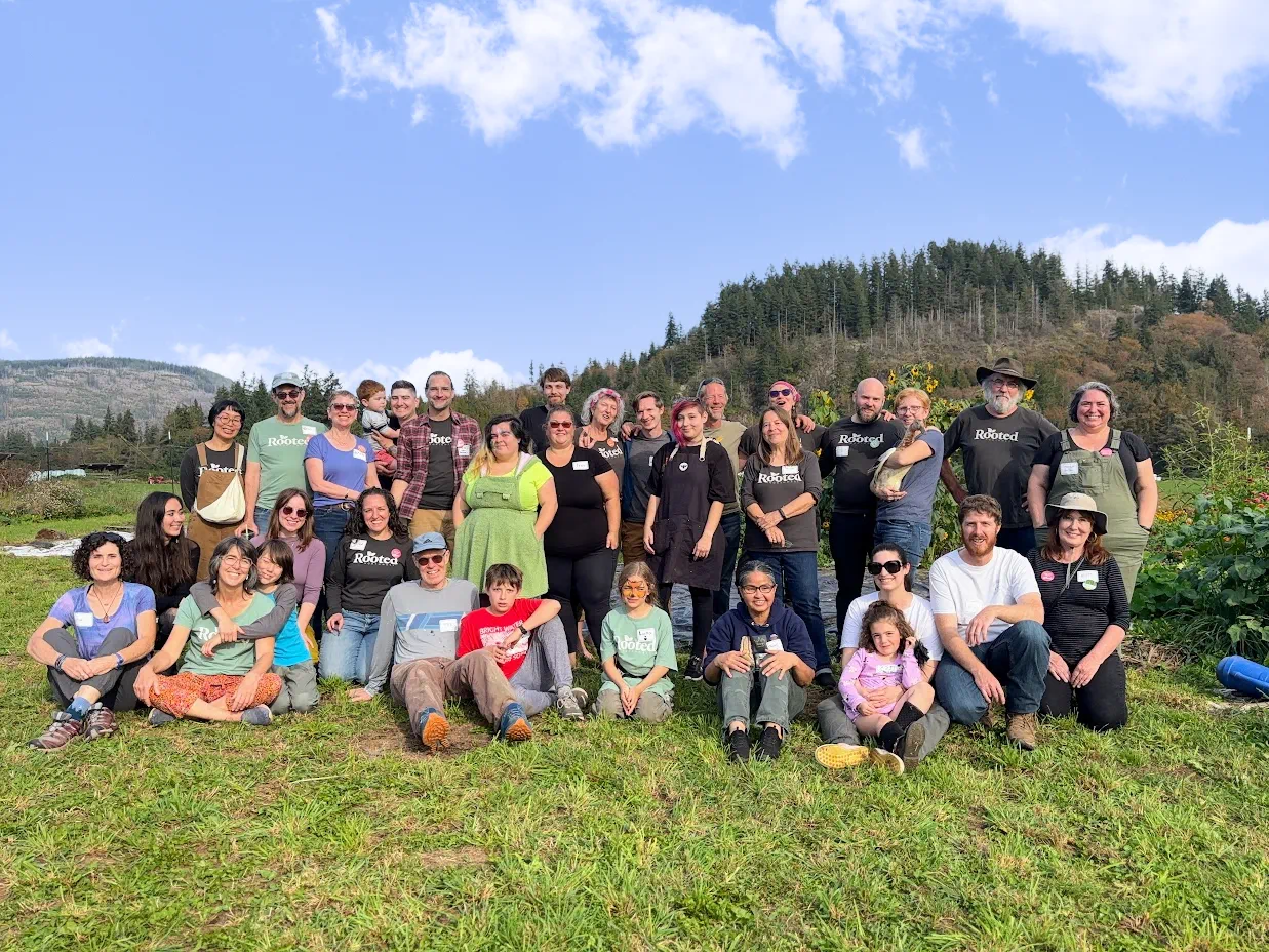 A large group of community members standing together outdoors on open land at Rooted Northwest.