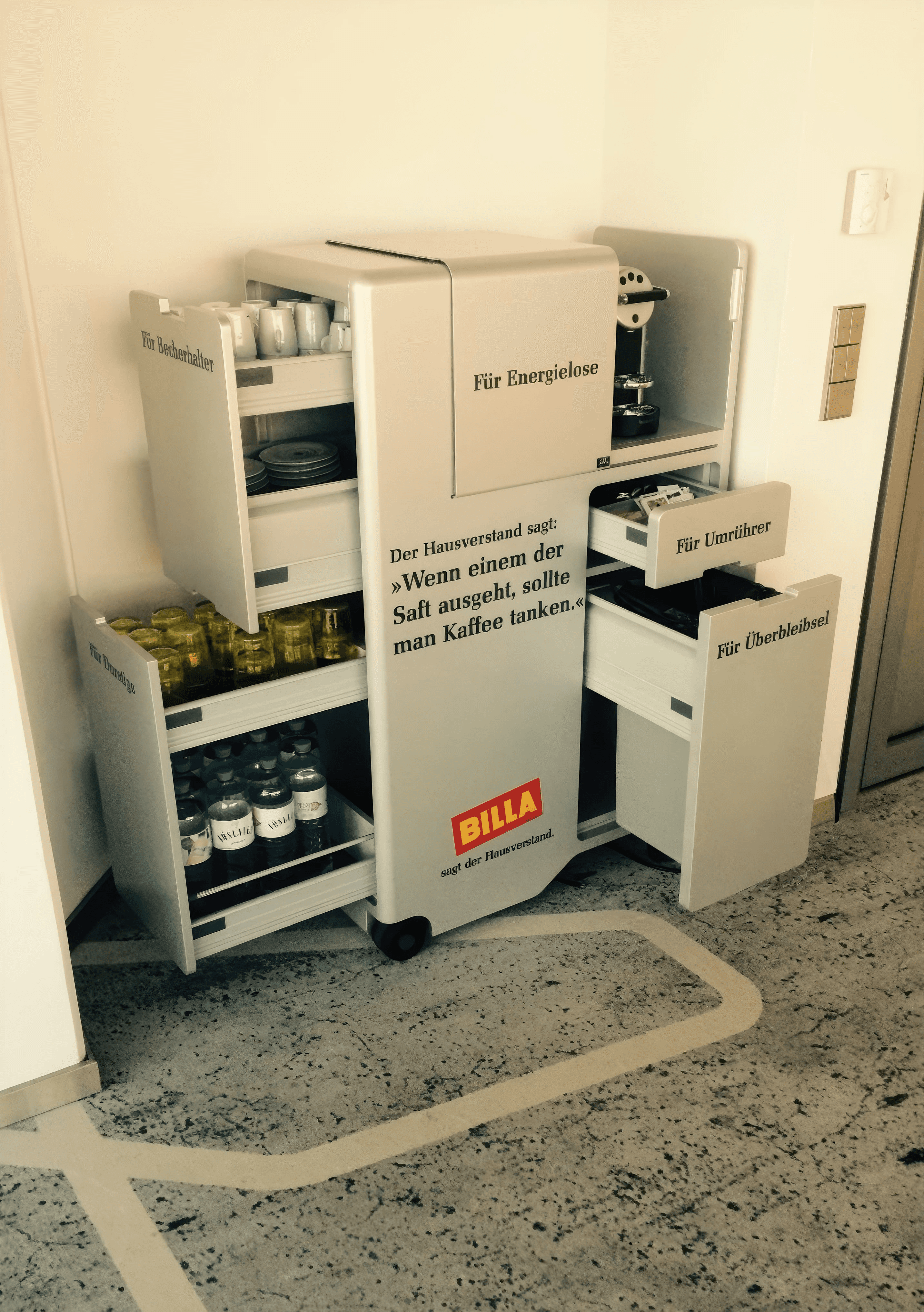 MW Interior  - Mobiler Kaffeewagen mit integrierter Kaffeemaschine, Schubladen für Tassen, Getränke und Zubehör mit Billa-Branding" Beschreibung: Maßgefertigter Catering-Rollwagen mit integrierter Kaffeemaschine, beschrifteten Schubladenauszügen und Billa-Branding – eine witzige wie funktionale Lösung für die Pausenversorgung im Büroalltag.